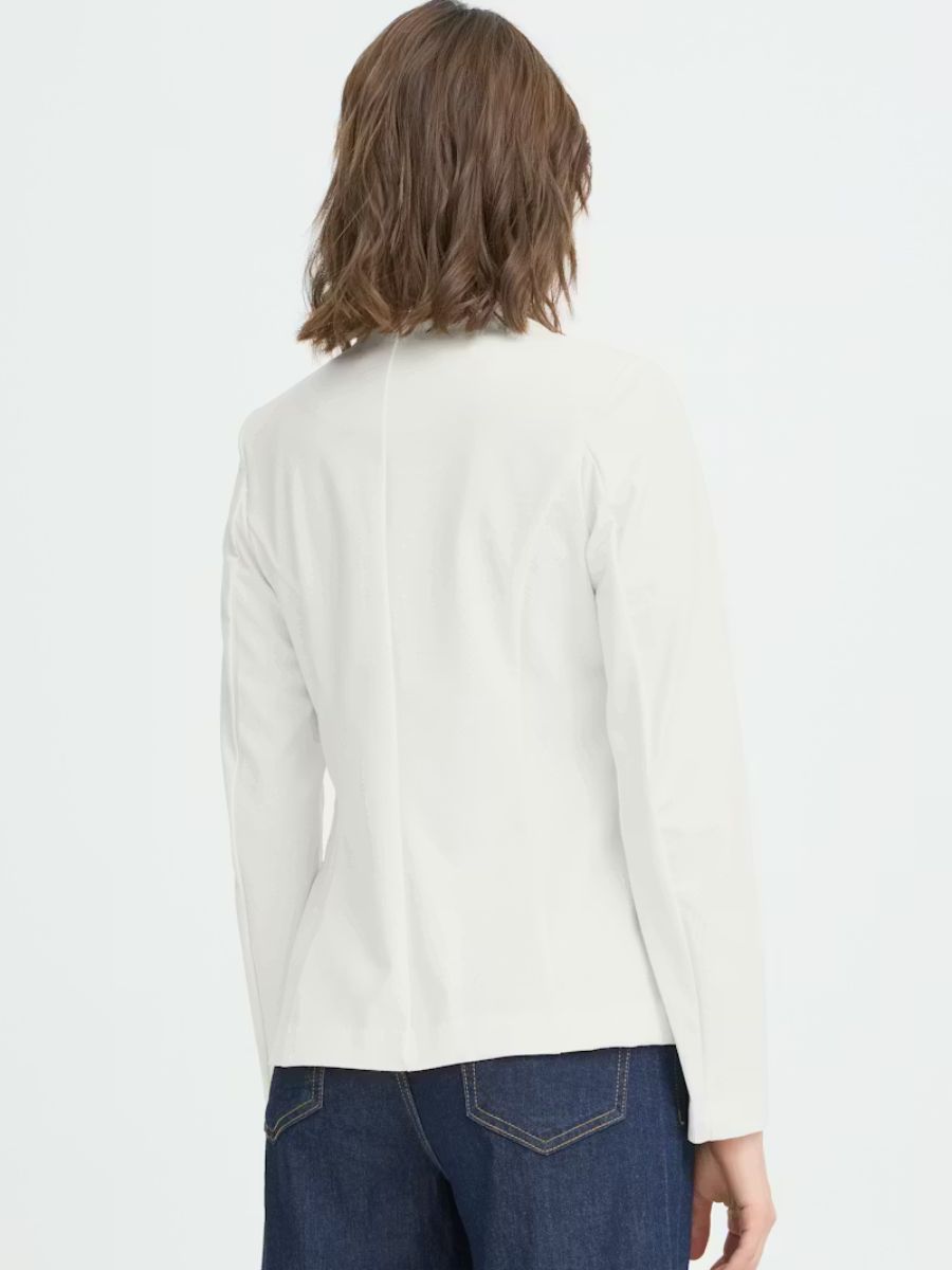 Back view of an off-white, long-sleeve tailored jacket paired with dark blue denim jeans on a model.