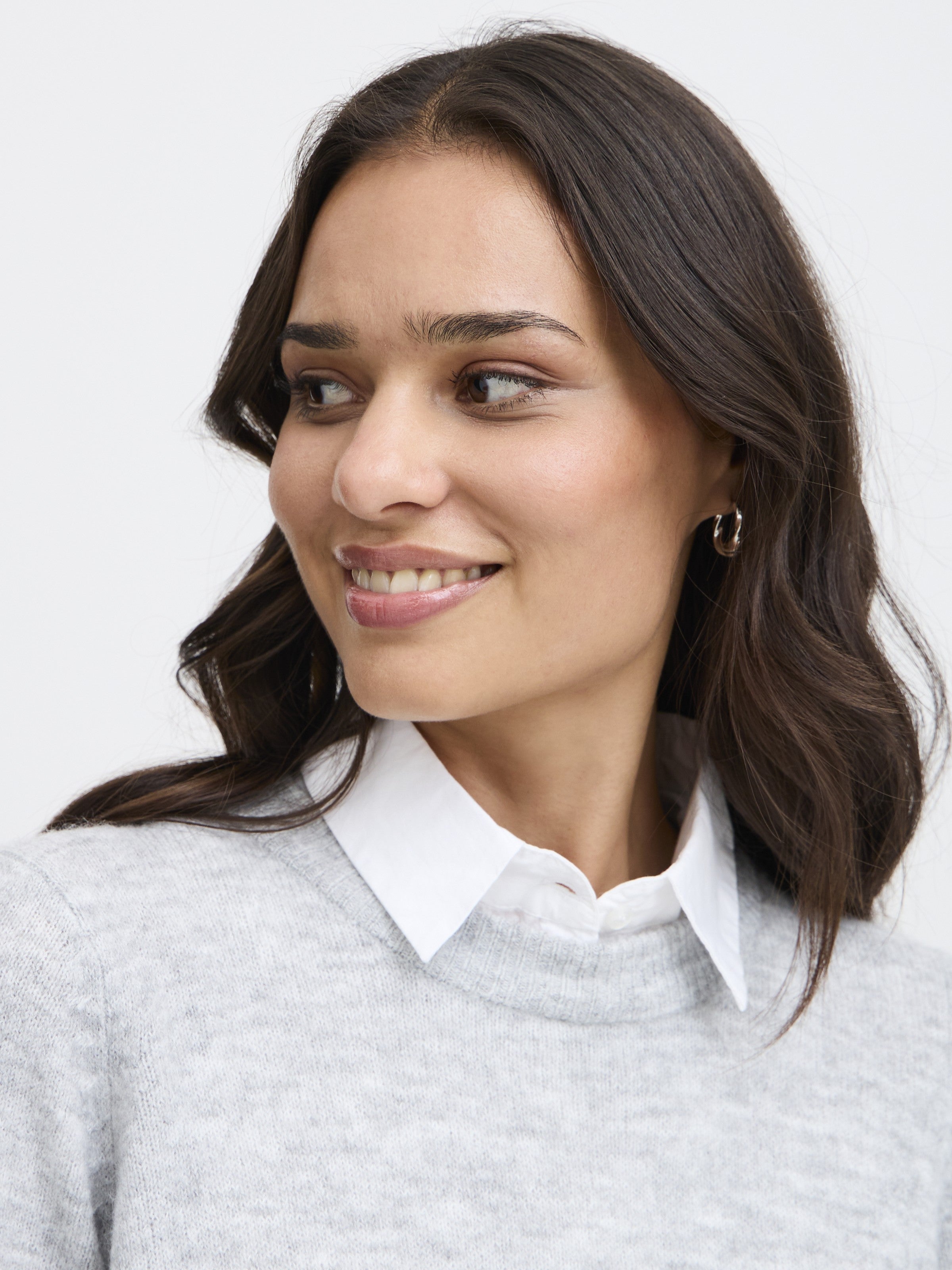 Close-up of a person wearing a white Fransa Removable Dickie Collar Insert under a grey sweater, styled with small hoop earrings.