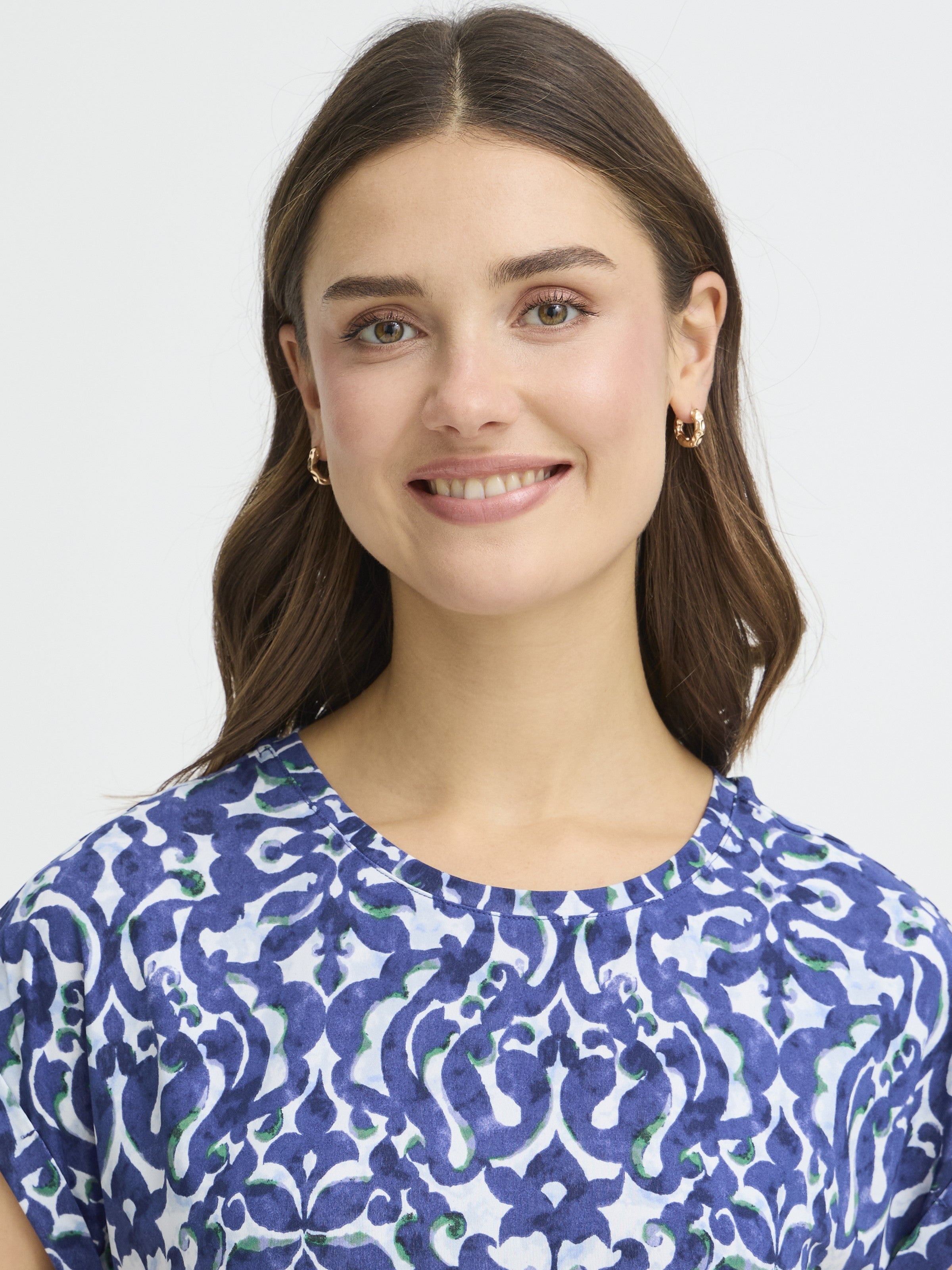Close-up of a smiling person wearing a blue patterned Fransa Seen Short Sleeve Crew Neck Top by Fransa.