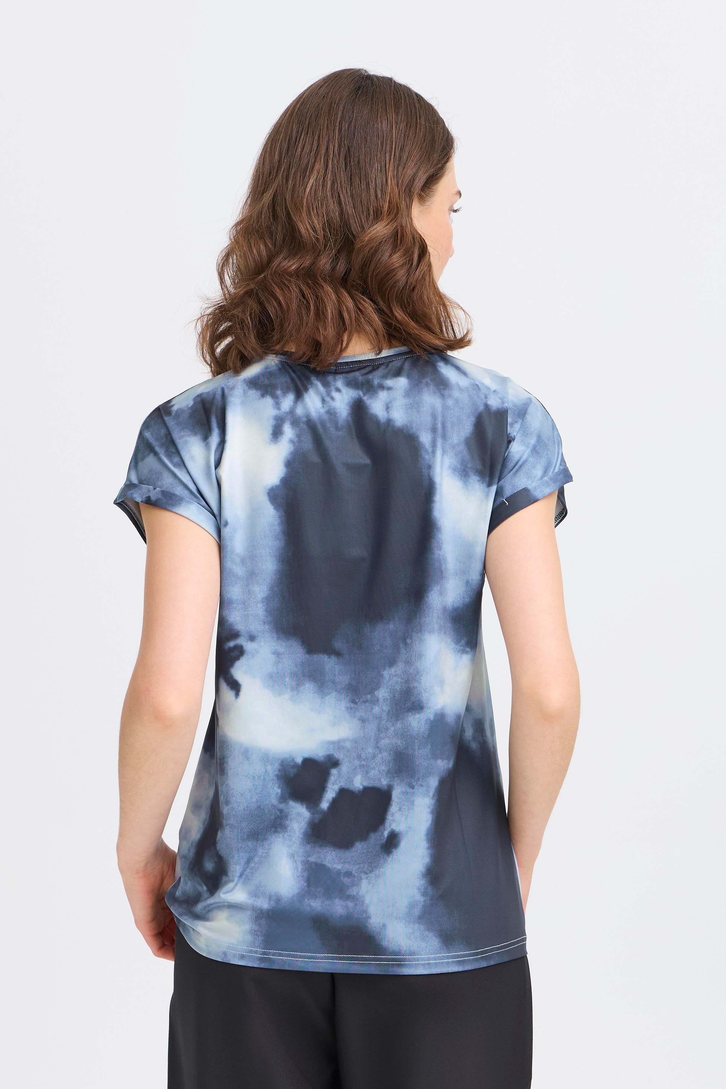 Back view of tie-dye Fransa Seen Short Sleeve Crew Neck Top in blue tones paired with black bottoms