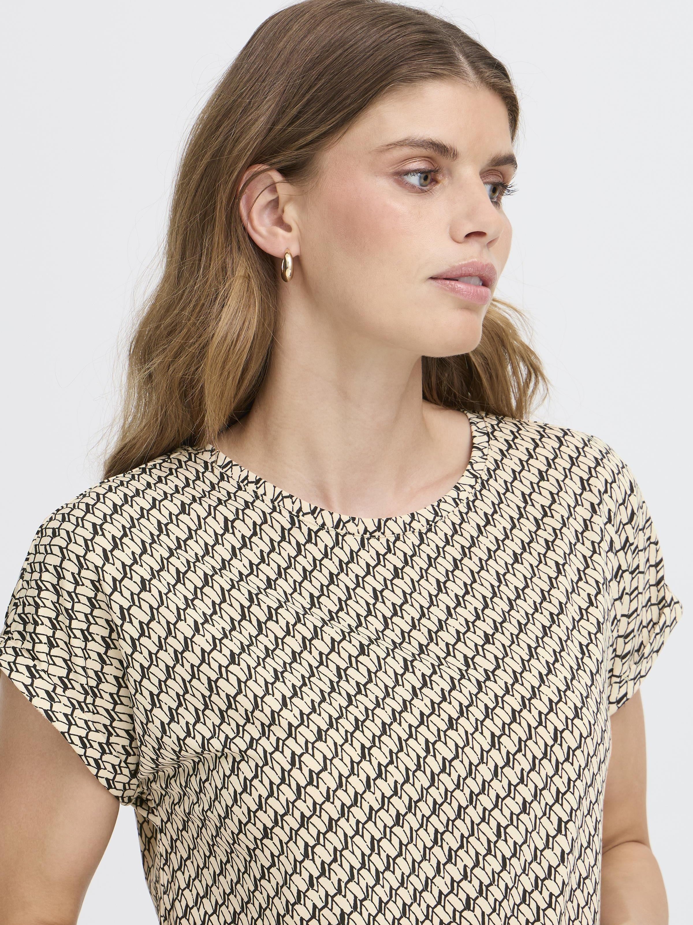 Fransa Seen Short Sleeve Crew Neck Top in cream and black geometric pattern with gold hoop earrings and natural hair.