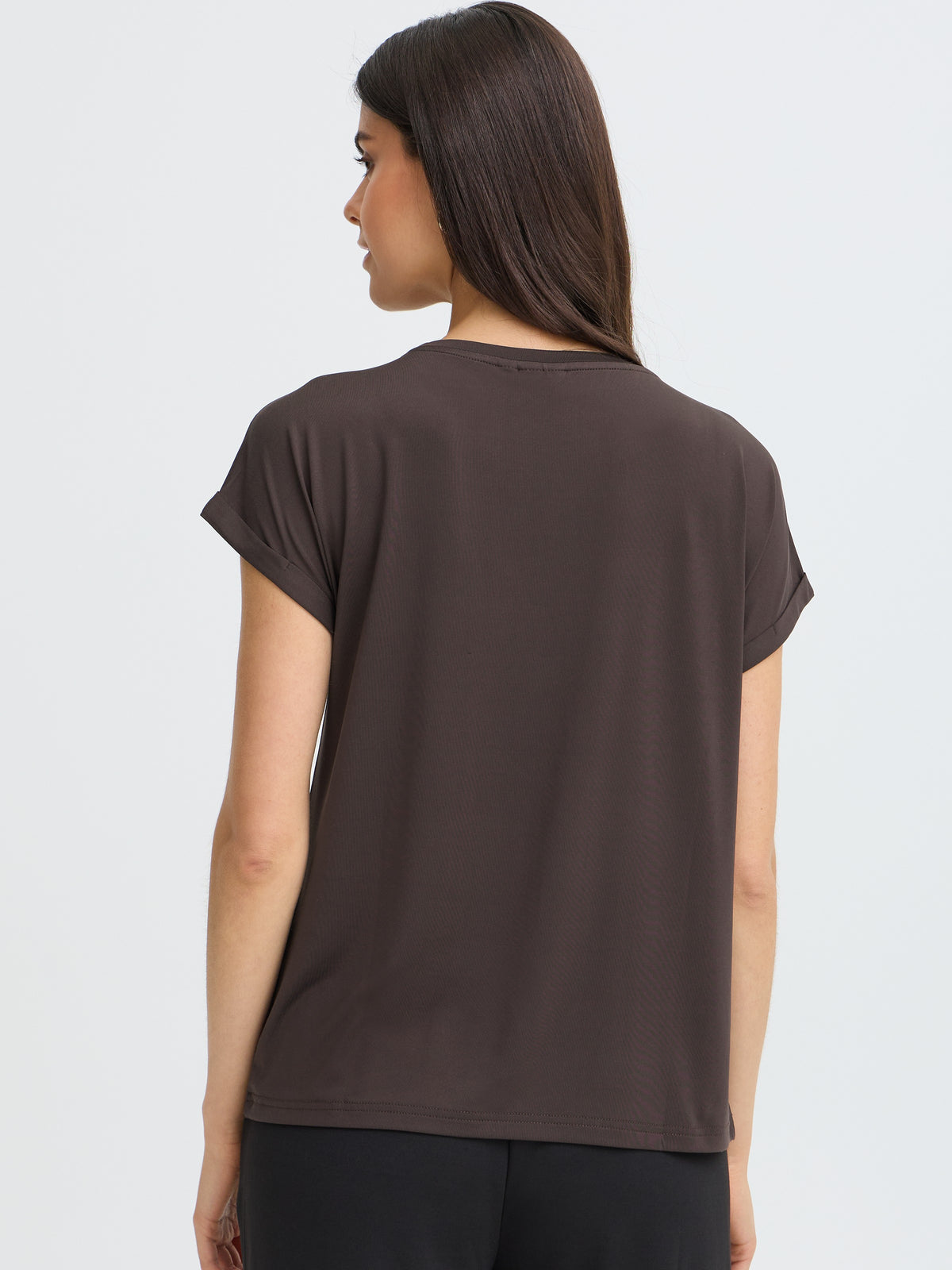 Back view of a woman in a dark brown short-sleeve top and black trousers