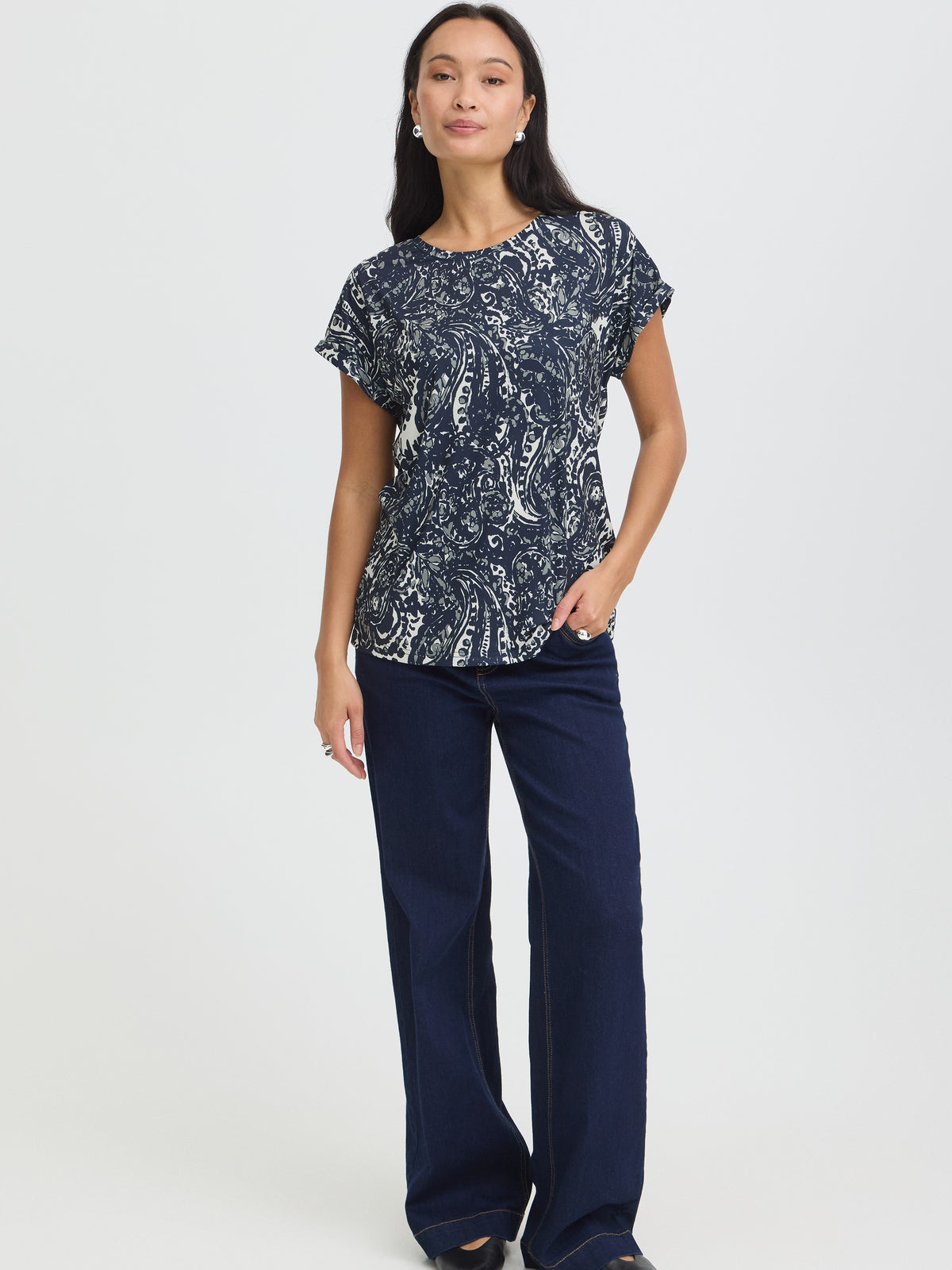 Navy paisley short-sleeve top paired with dark wide-leg trousers against a light gray background