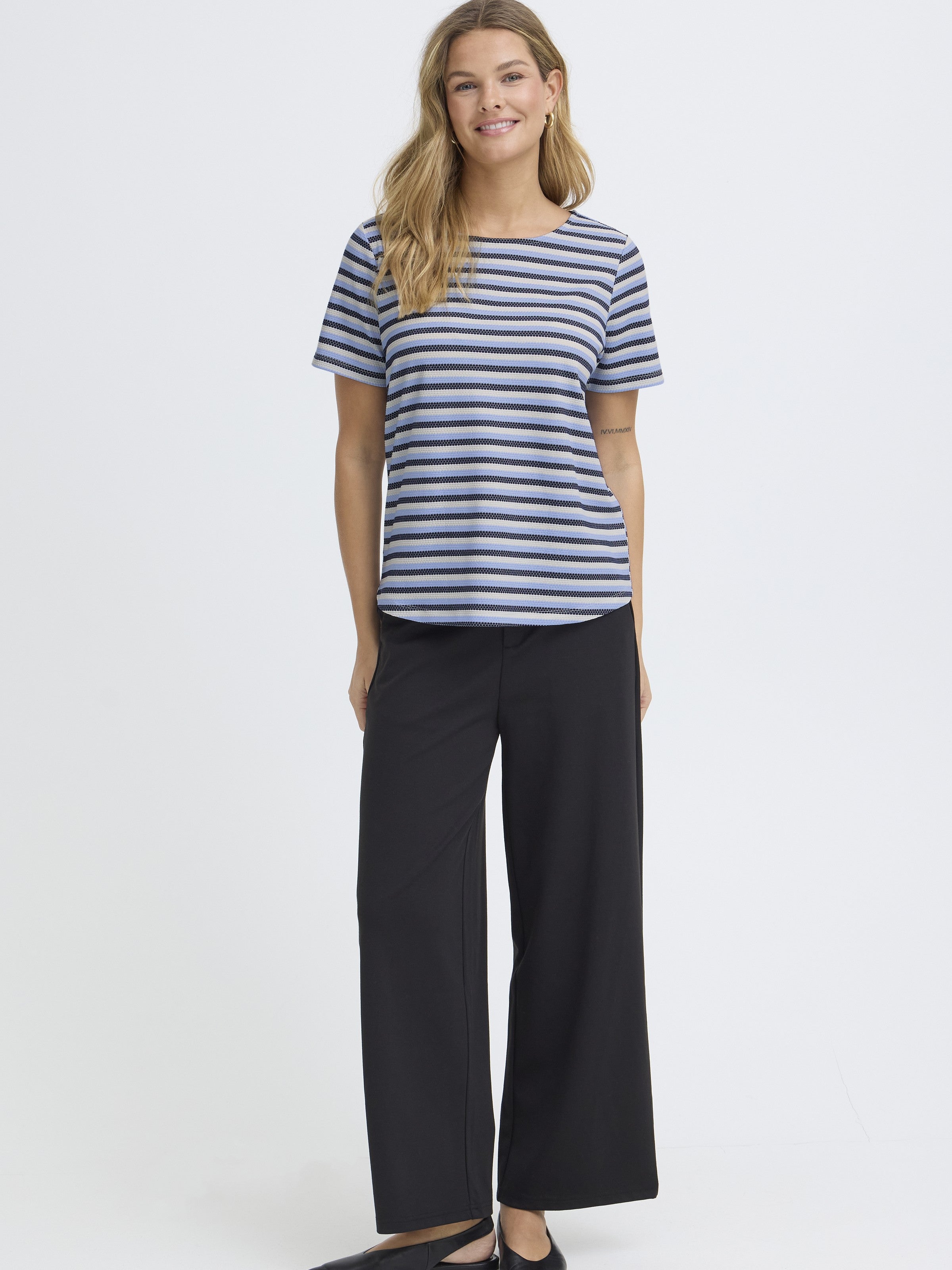 Model wearing Fransa Josie Striped Short Sleeve Top in blue and white stripes paired with black wide-leg pants