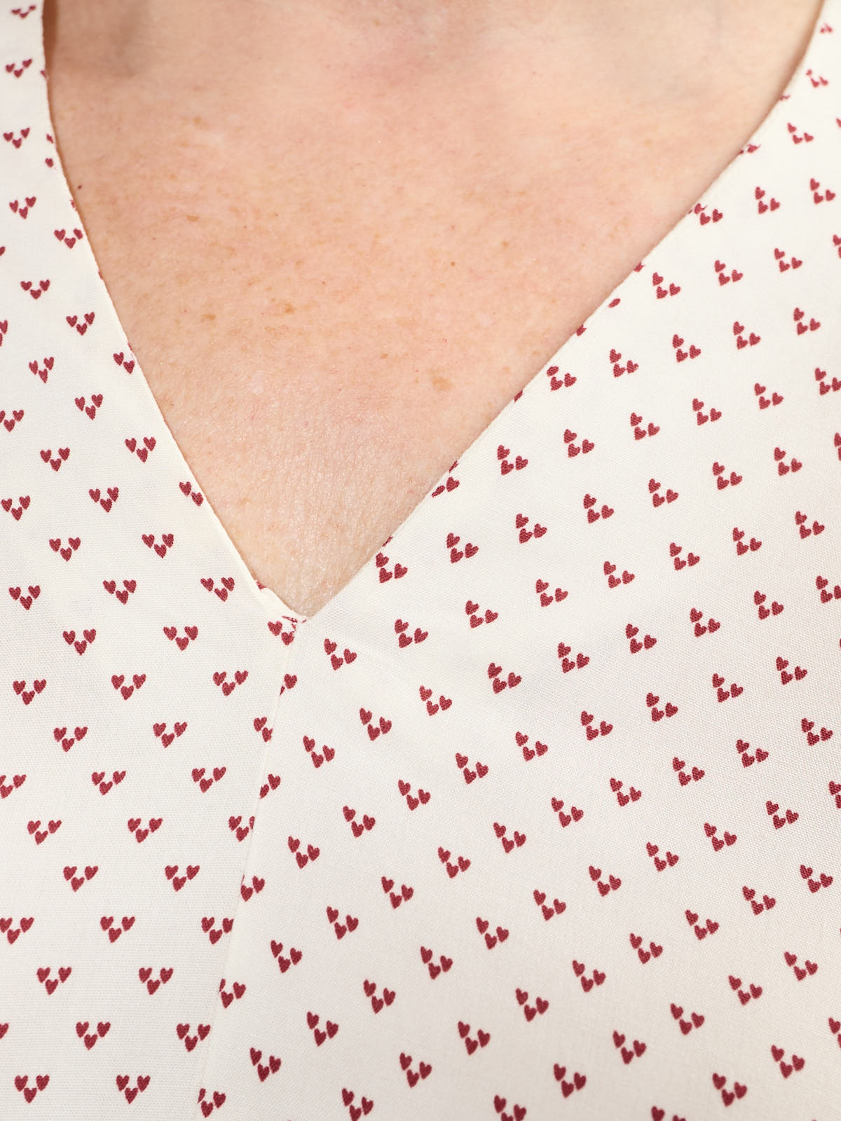 Close-up of cream fabric with red heart print on the Fransa Justine Heart Print Short Sleeve V-Neck Top by Fransa.