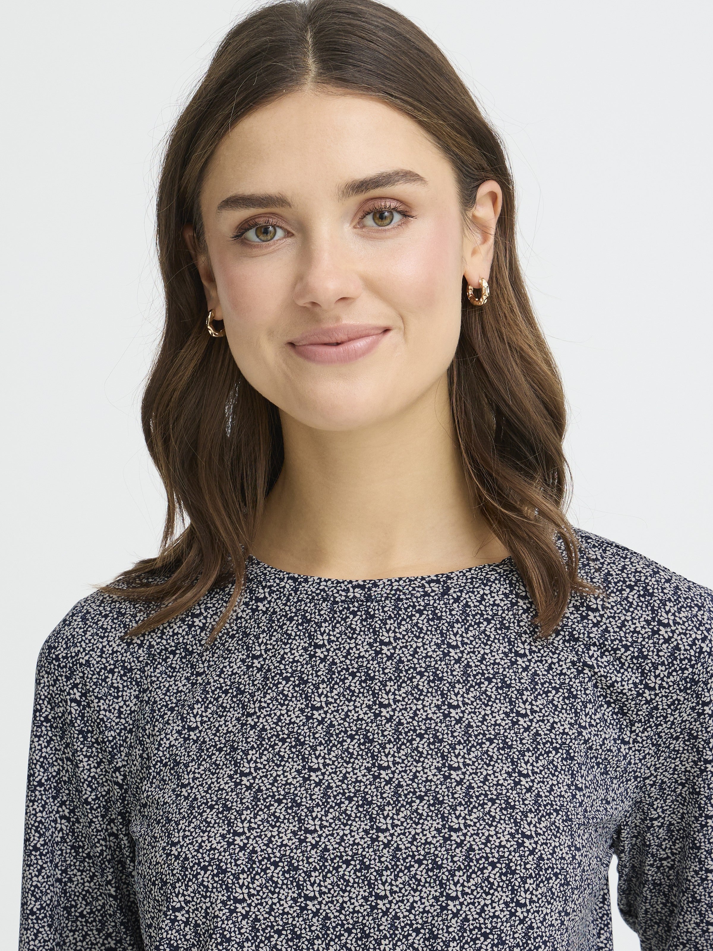 Smiling individual wearing a navy floral Fransa Seen Three-Quarter Sleeve Cuff Top by Fransa in a close-up portrait.