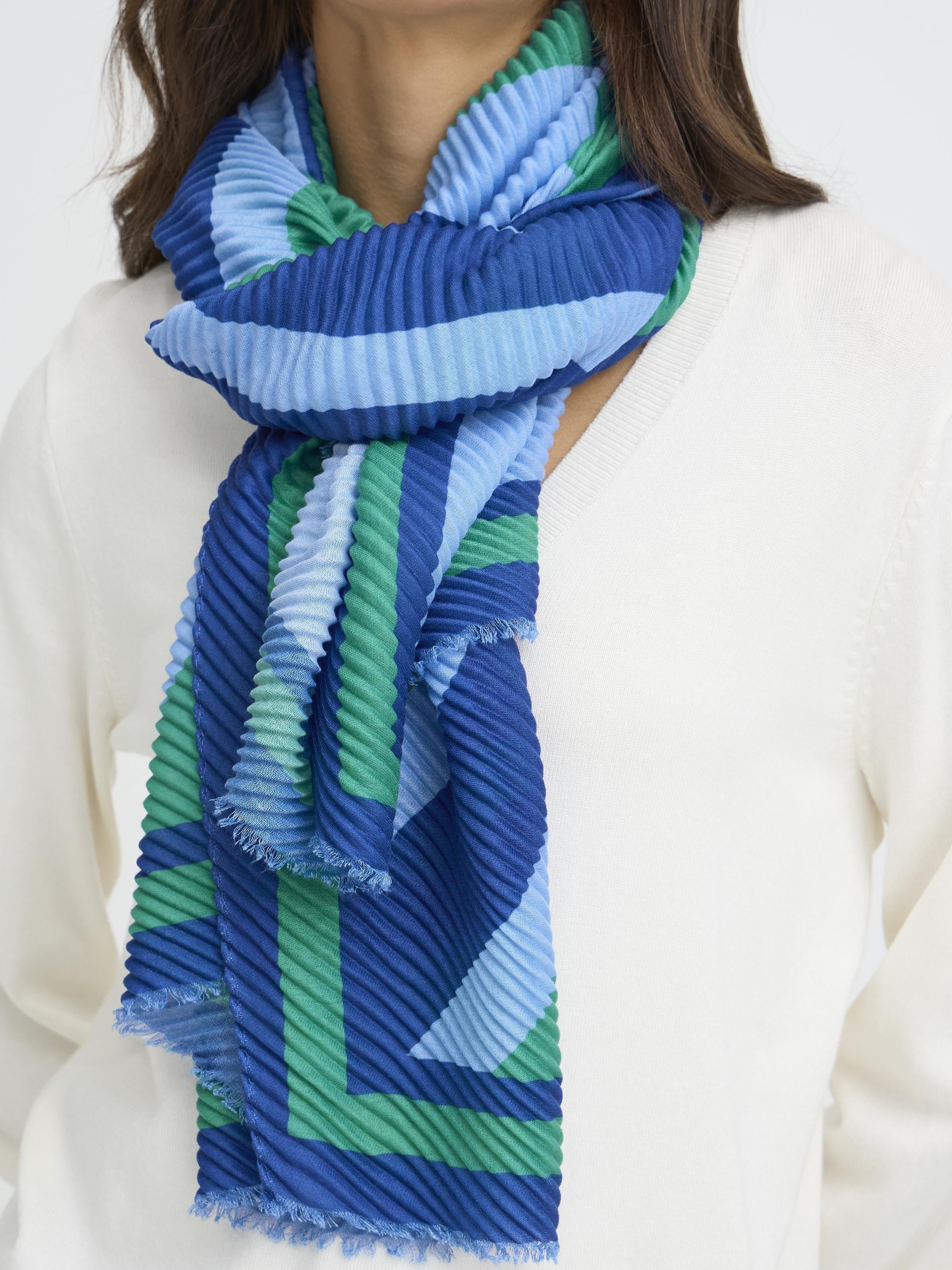 Fransa Plisea Printed Lightweight Scarf in blue and green tones styled as an accessory with a white top.
