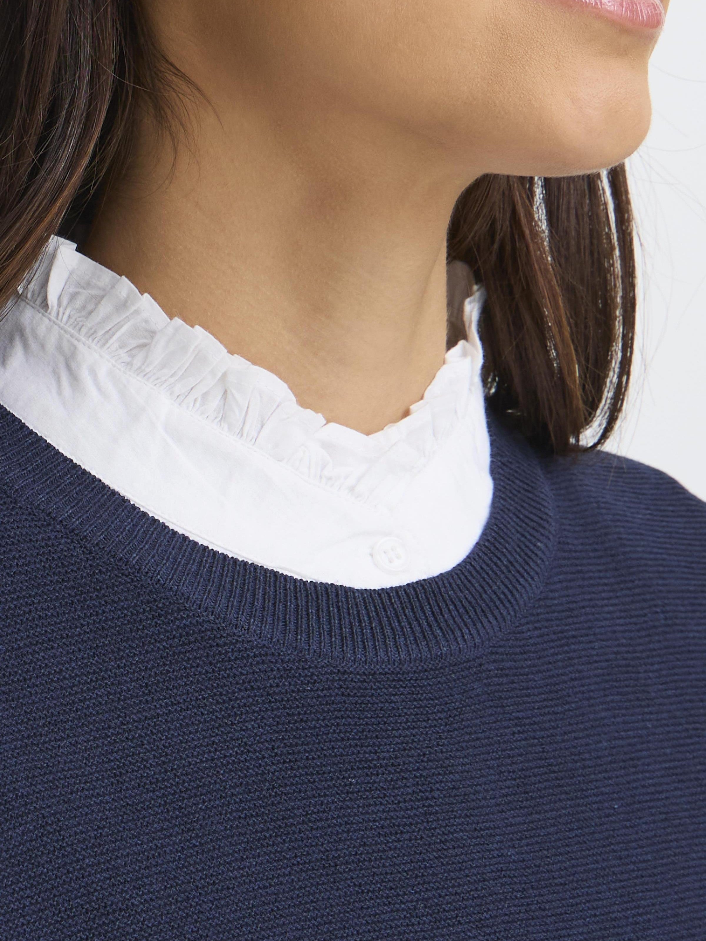 Fransa Somia Ruffle Dickie Collar in white layered under a navy knit sweater, showcasing delicate ruffled neckline detail