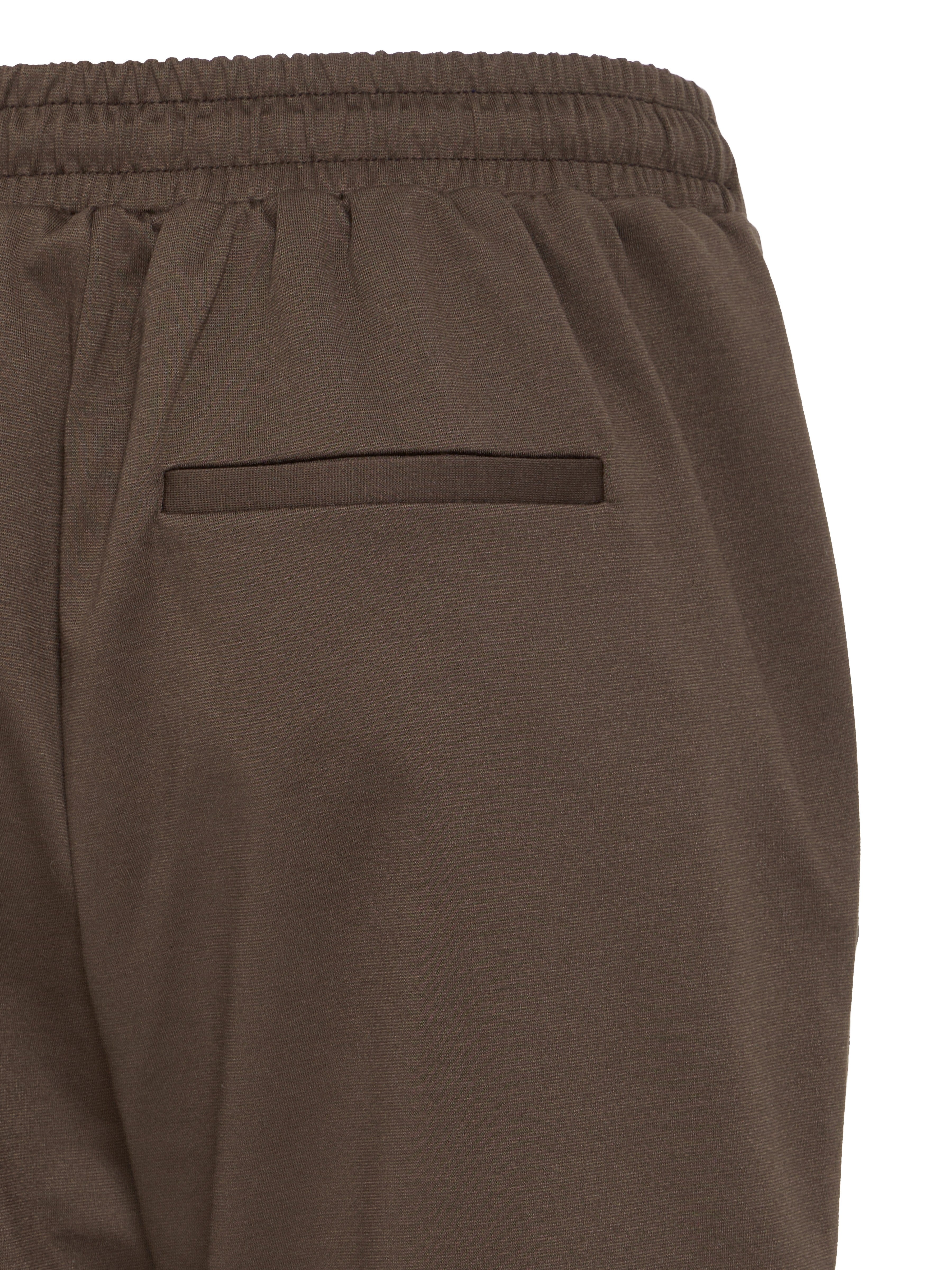 Close-up of brown elastic waistband pants featuring a single welt pocket on the back side.