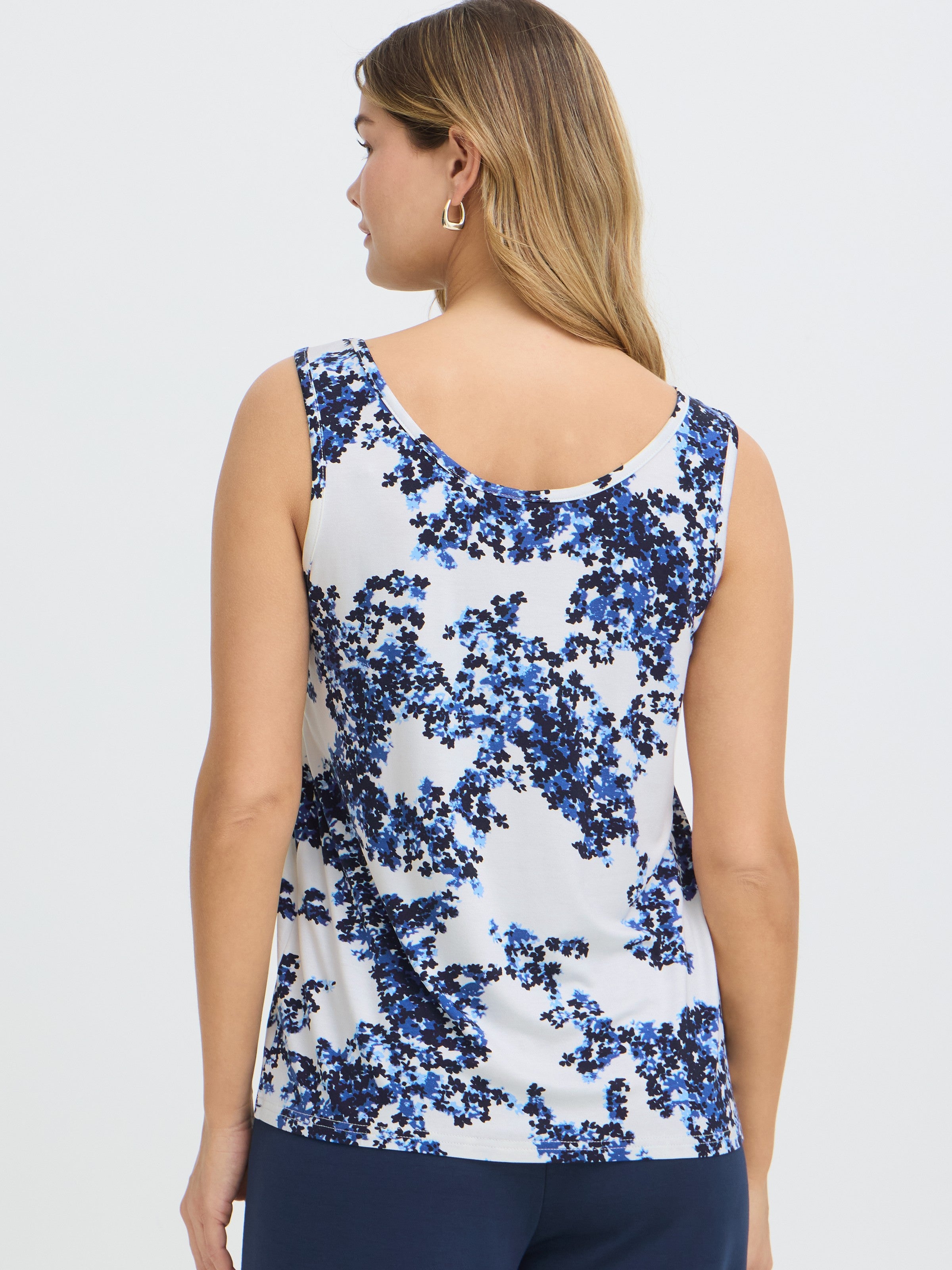 Sleeveless white top with blue and black floral print shown from the back on a light background.