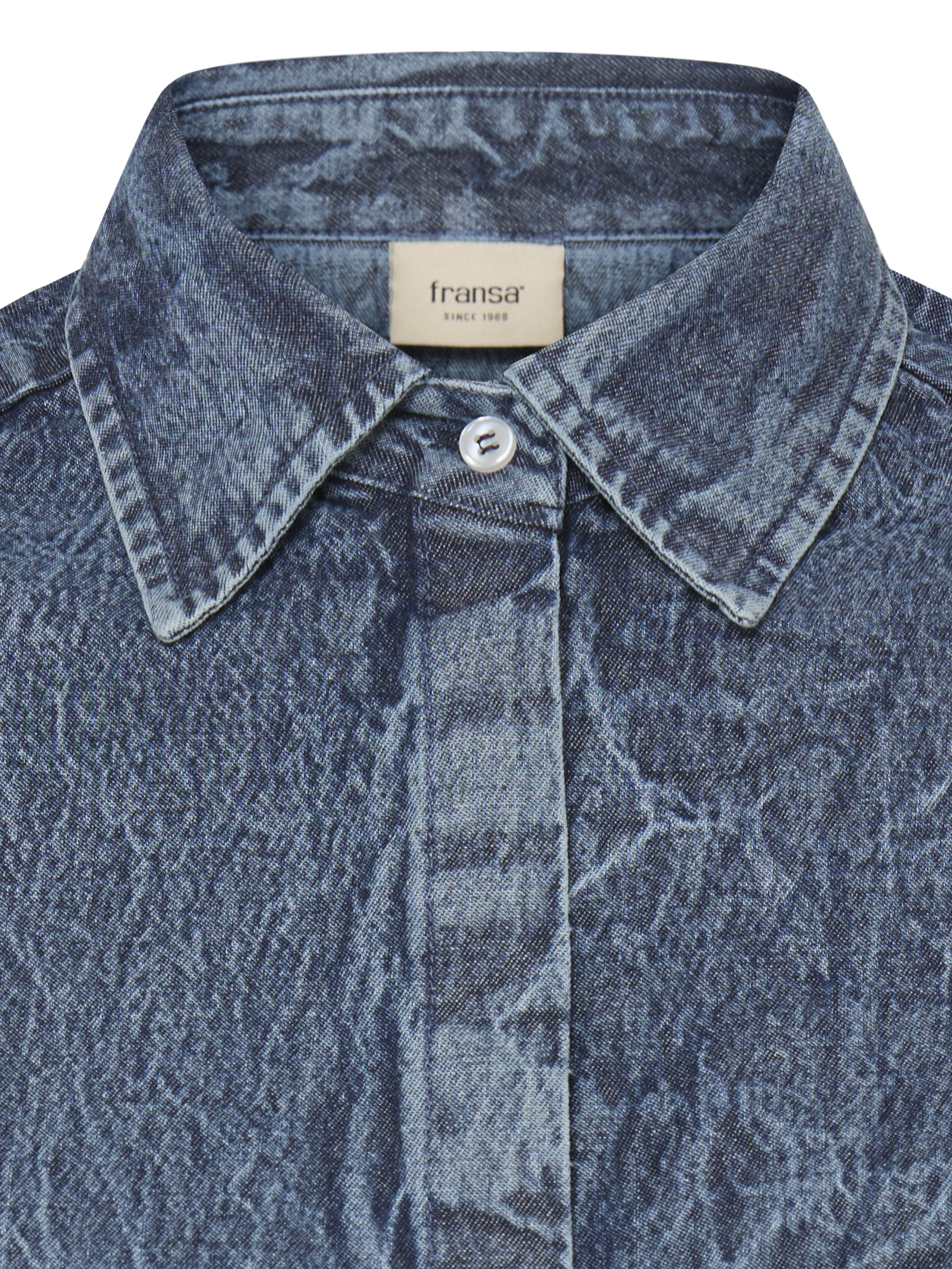 Close-up of faded blue denim jacket collar with visible stitching and a single button closure beneath the label.