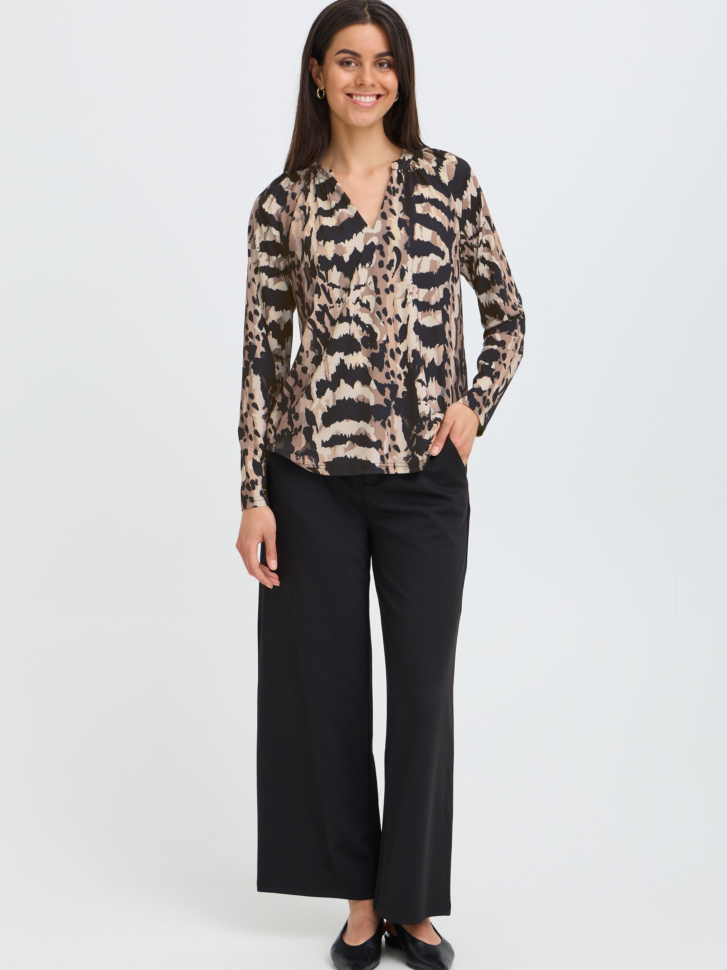 Model in a long-sleeve animal print blouse paired with black wide-leg pants and black flats on a white background.