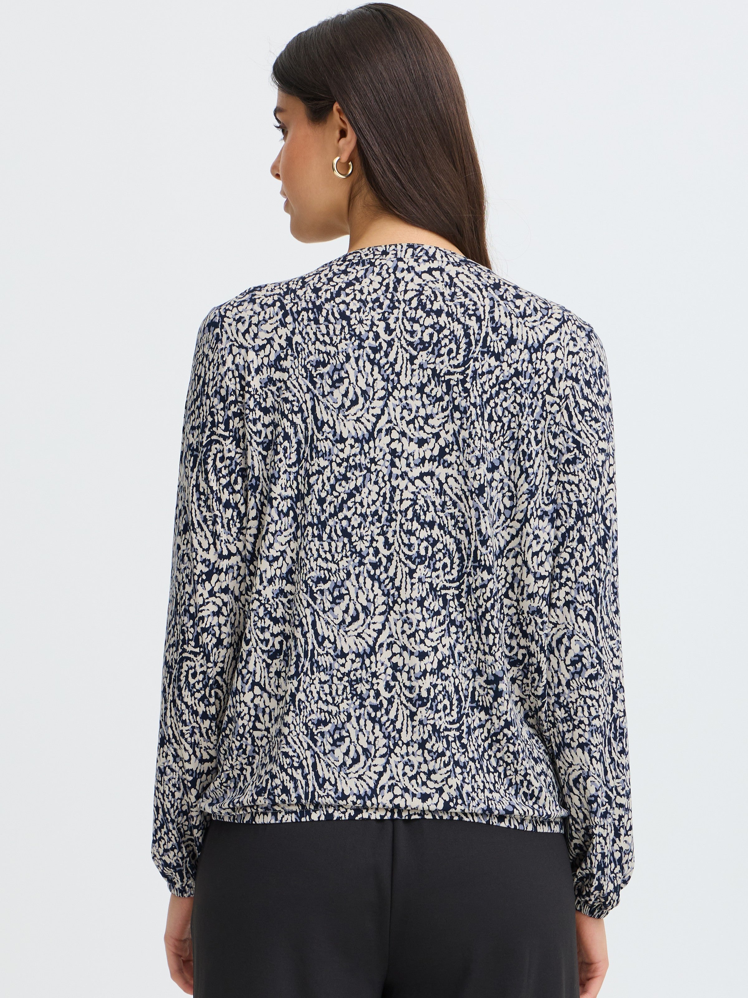 Back view of a long-sleeve top with a navy and white abstract leaf pattern and gathered cuffs.