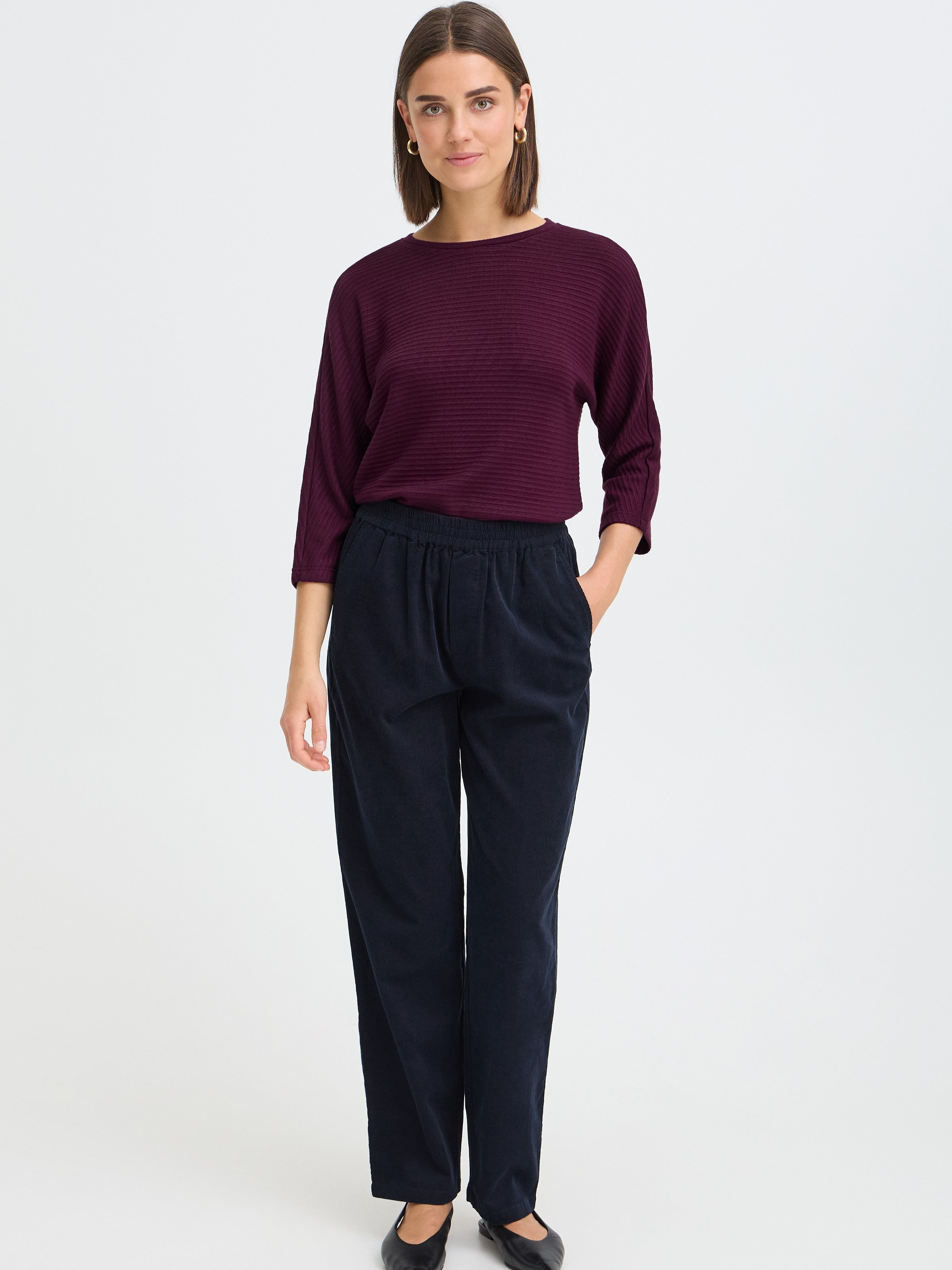 Slate blue pants with an elastic waistband paired with a textured plum long sleeve top and black flats.