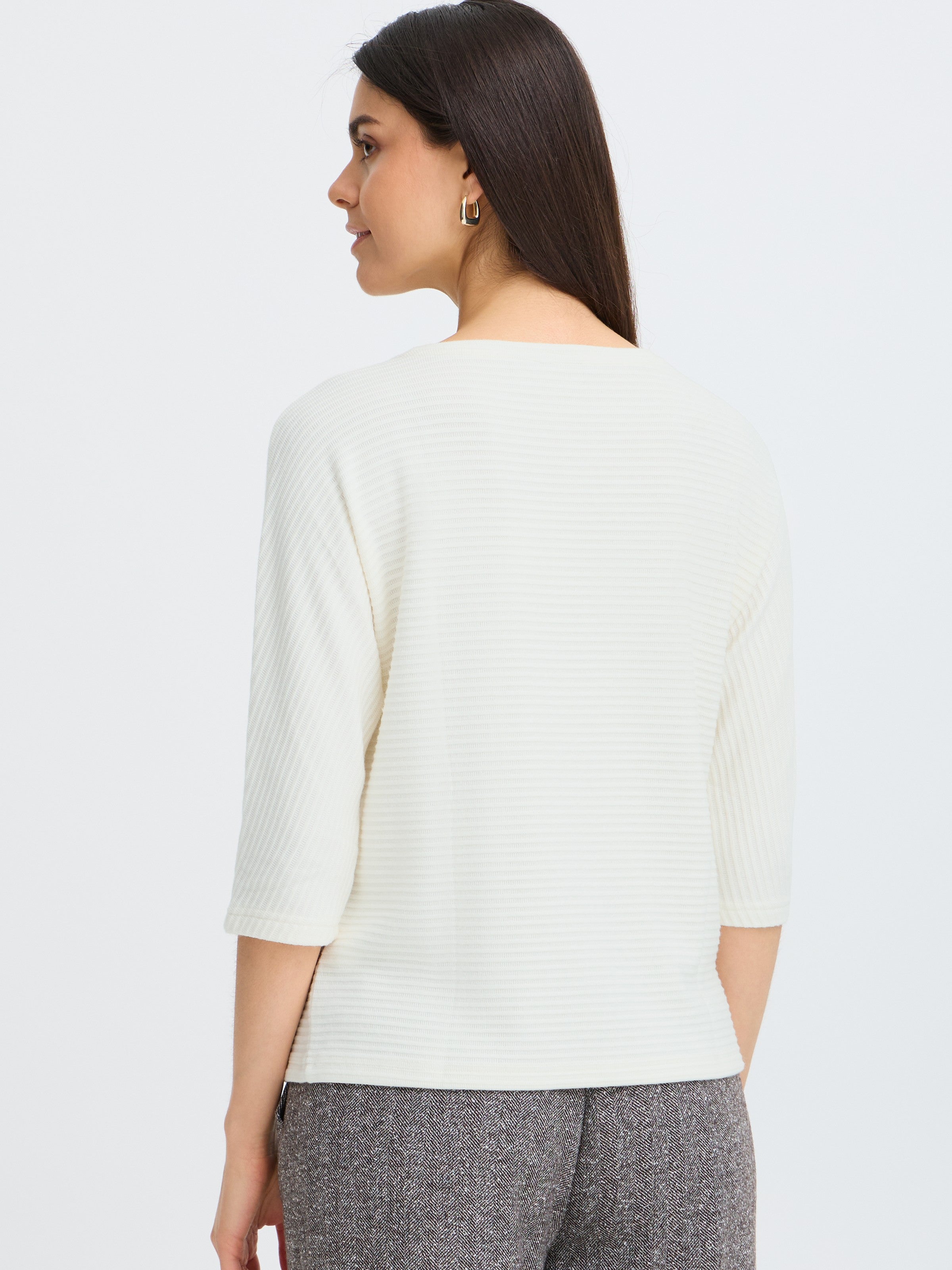 Back view of a ribbed textured white top with three-quarter sleeves paired with gray textured pants.