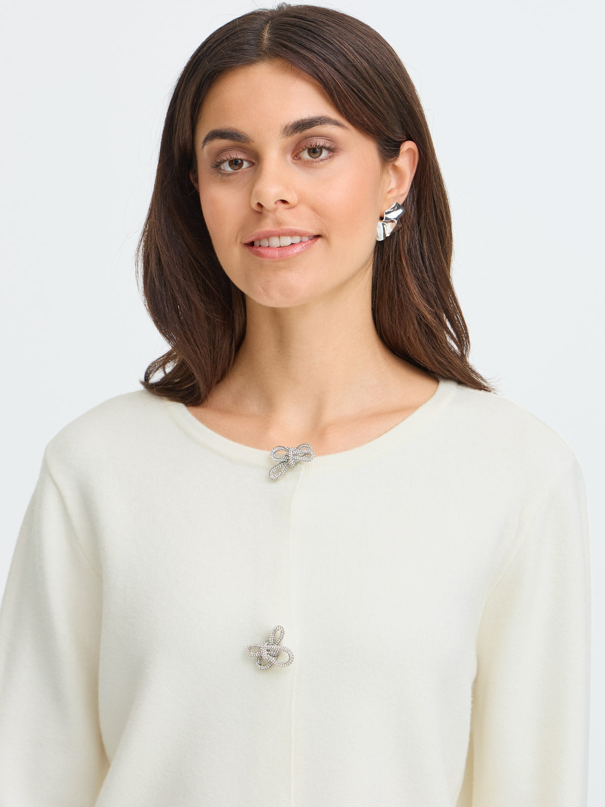 Portrait of a fashion model in a cream cardigan with floral brooches and earrings