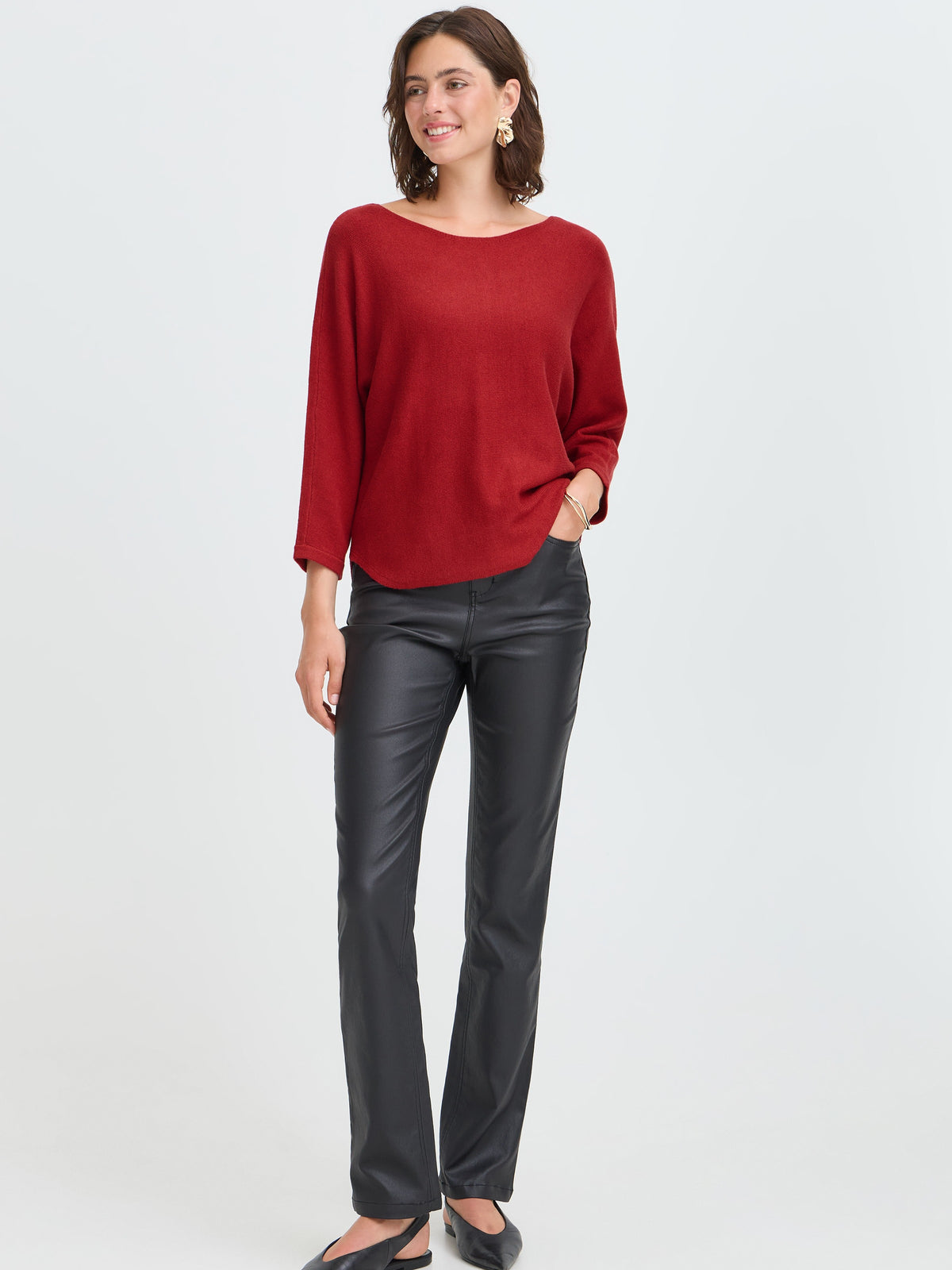 Red sweater with black leather pants and flats against a light background