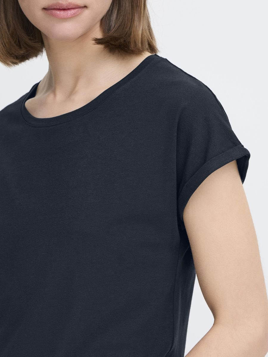 Close-up of a navy blue short-sleeve top with rolled cuffs on a model against a light background.