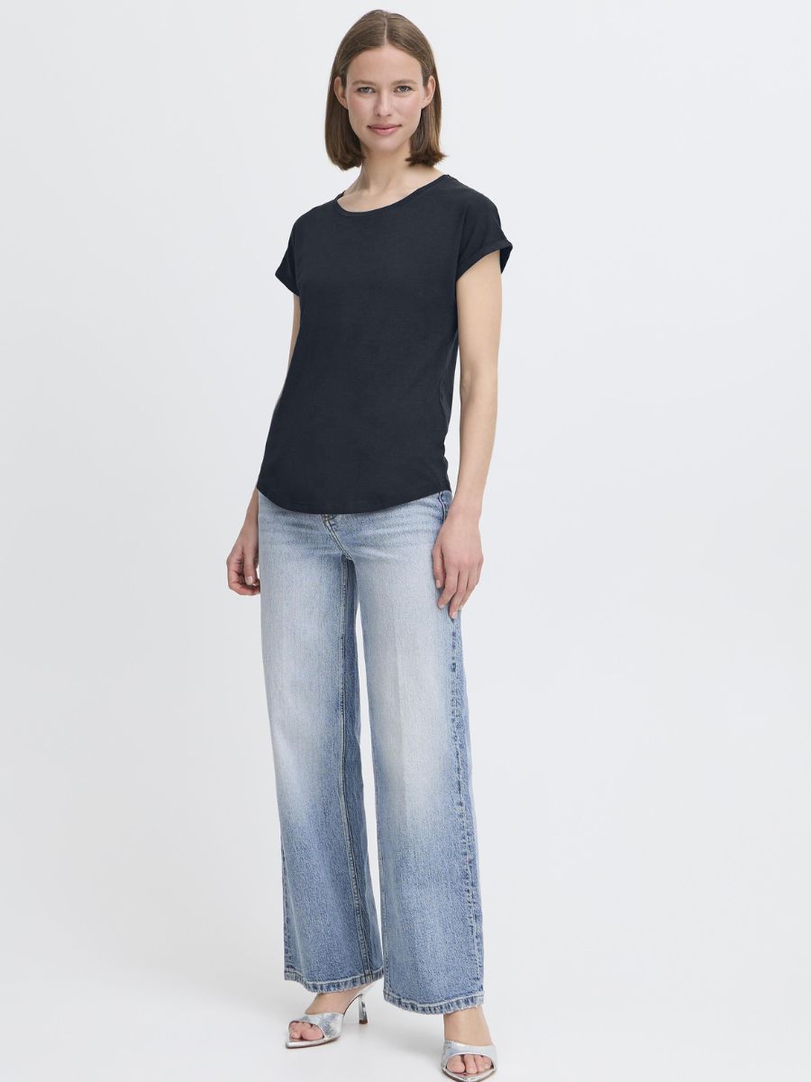 Person wearing a navy short-sleeve top paired with light blue wide-leg denim jeans and silver open-toe heels.
