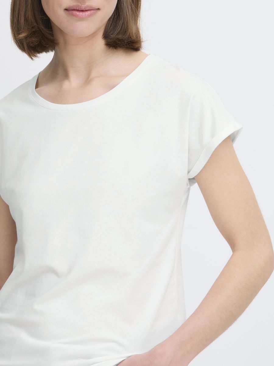 Close-up of a person wearing a plain off-white short-sleeve T-shirt with a round neckline.