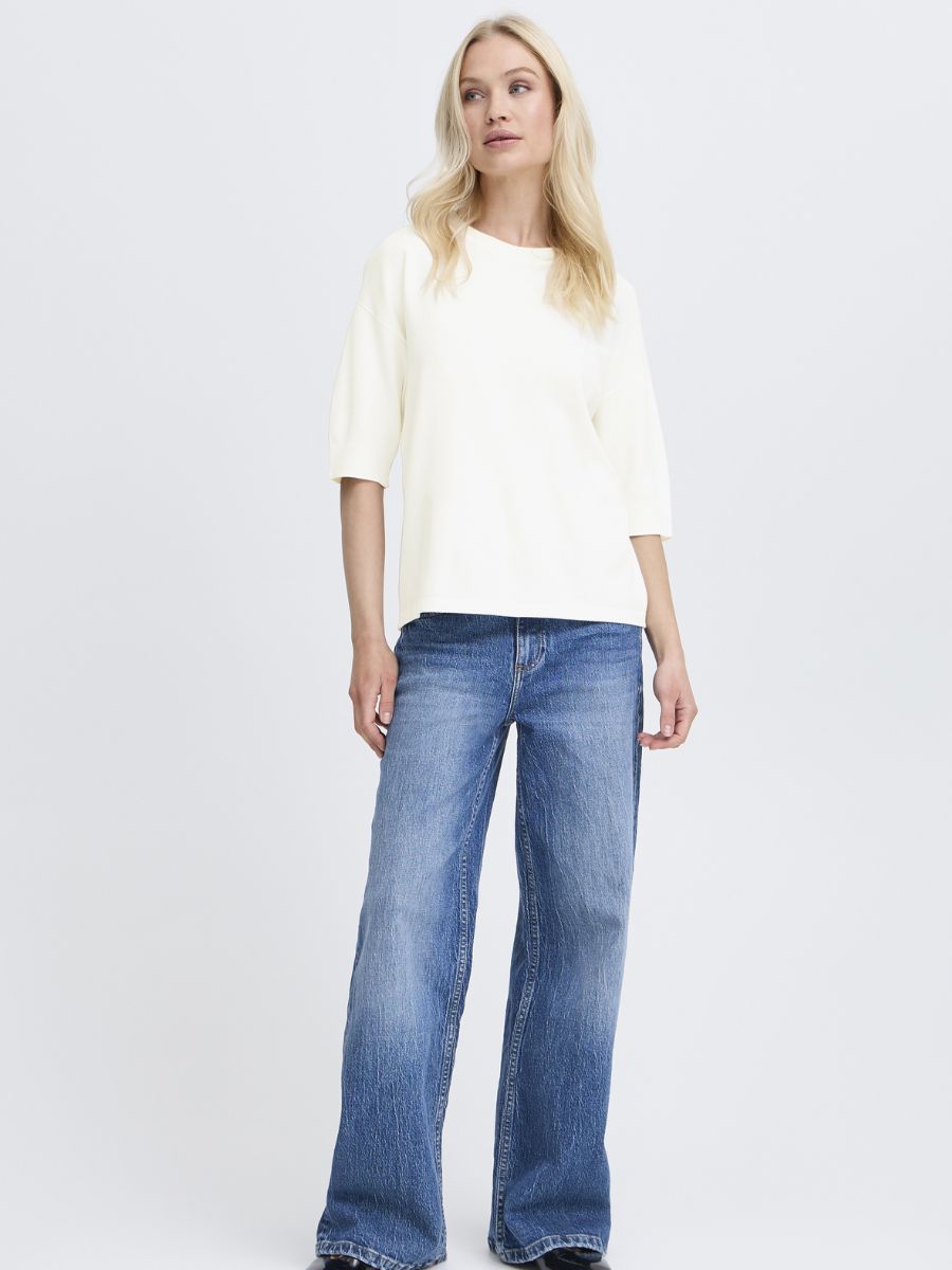 Model in a white B. Young Morla Short Sleeve Crew Top paired with blue denim wide-leg jeans by B. Young
