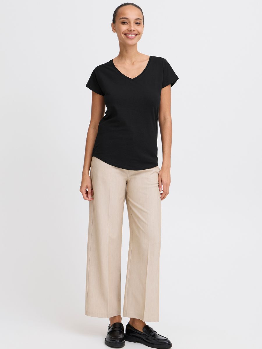 Model wearing B. Young Pamila V-Neck Short Sleeve Tee in black paired with beige pants and black loafers by B. Young.