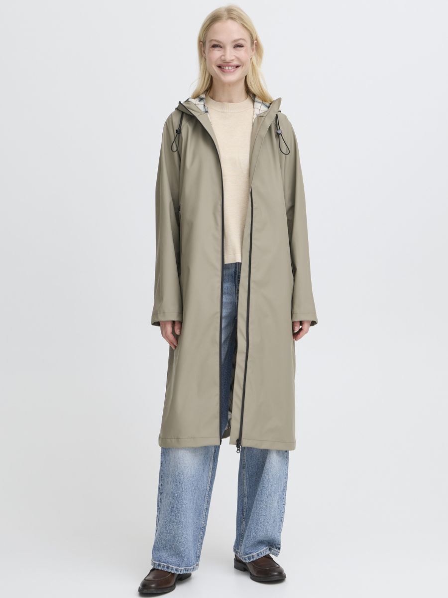 Model in beige layered outfit featuring B. Young Avan Long Rain Coat by B. Young, paired with blue jeans and dark shoes