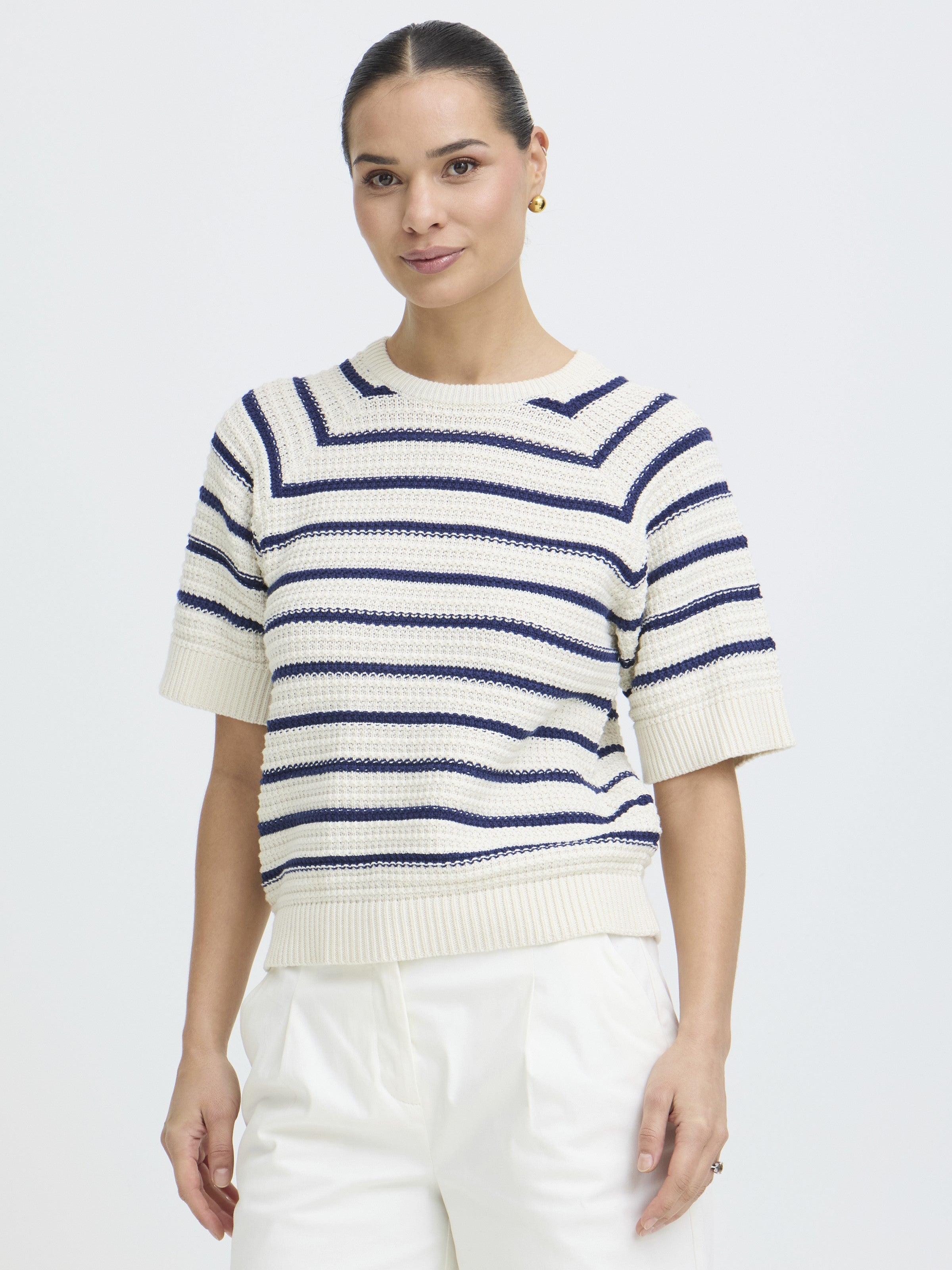 Short-sleeve cream knit top with navy horizontal stripes and ribbed edges styled with white pants