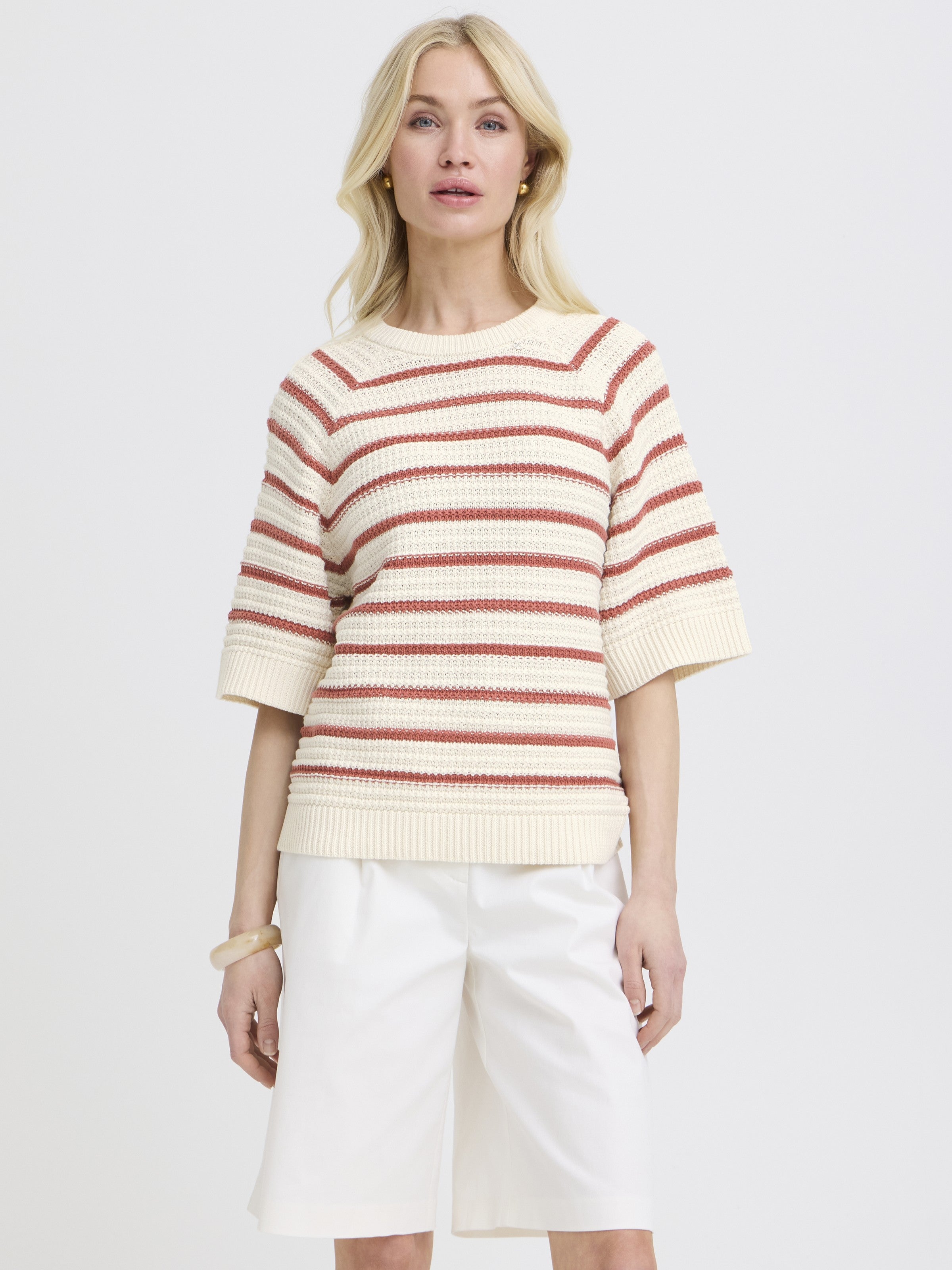 Cream and rust striped knit short-sleeve sweater paired with white knee-length shorts on a light background.