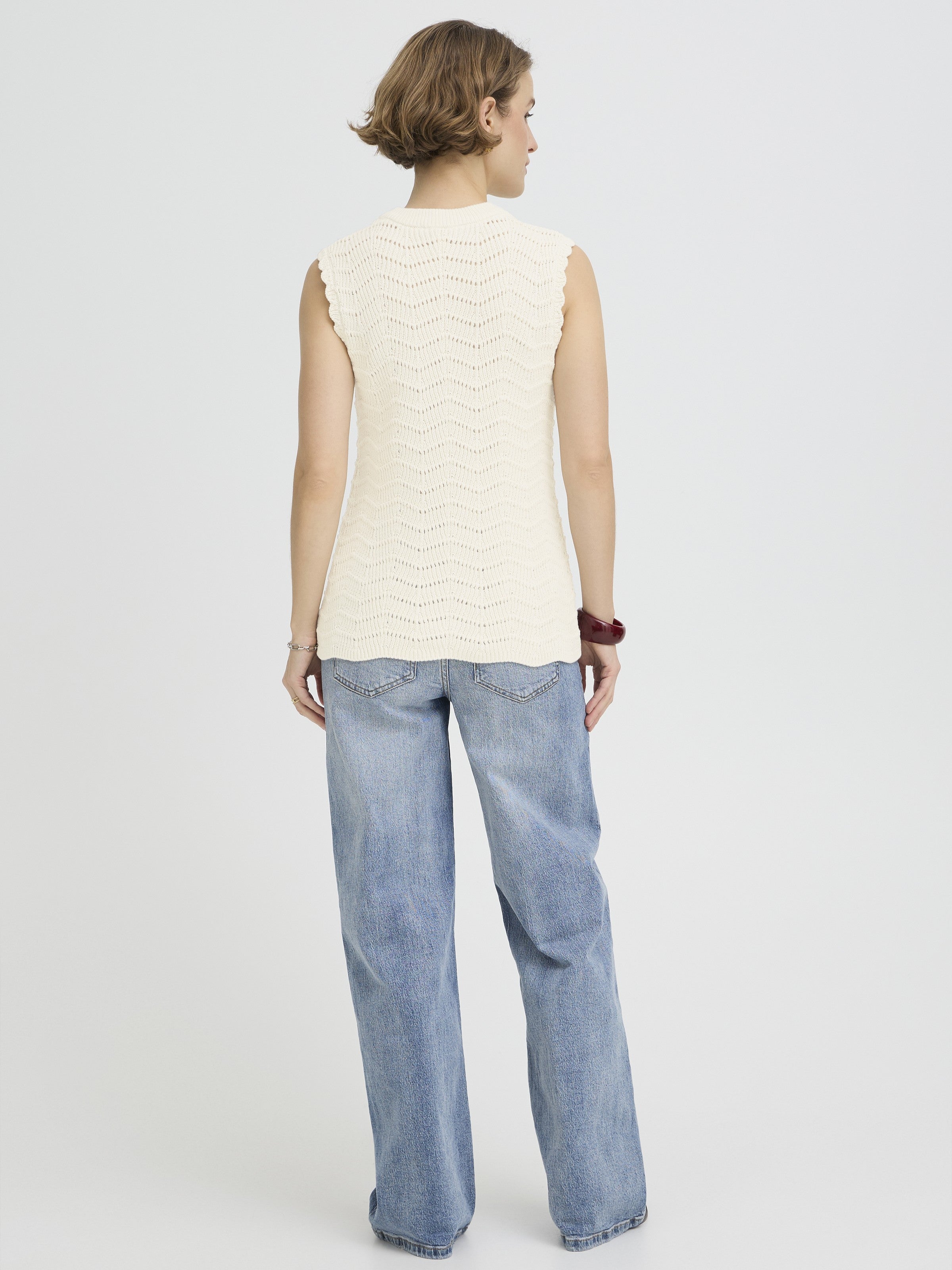 B. Young Nero Cotton Sleeveless Crew Neck Knit Top in beige with a textured knit pattern, paired with casual blue denim jeans.