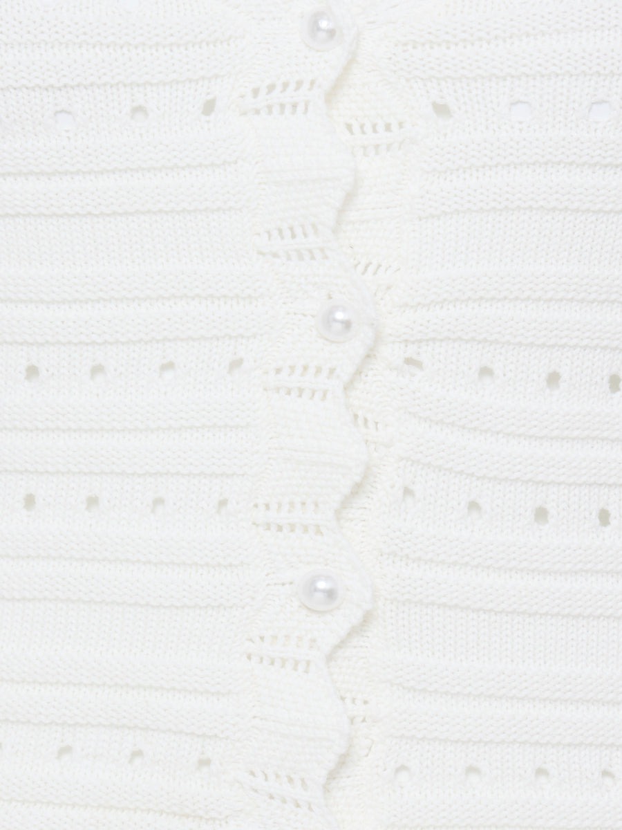 Close-up of white knit fabric with pearl buttons on the B. Young Naski Pearl Cardigan, showcasing detailed stitching.