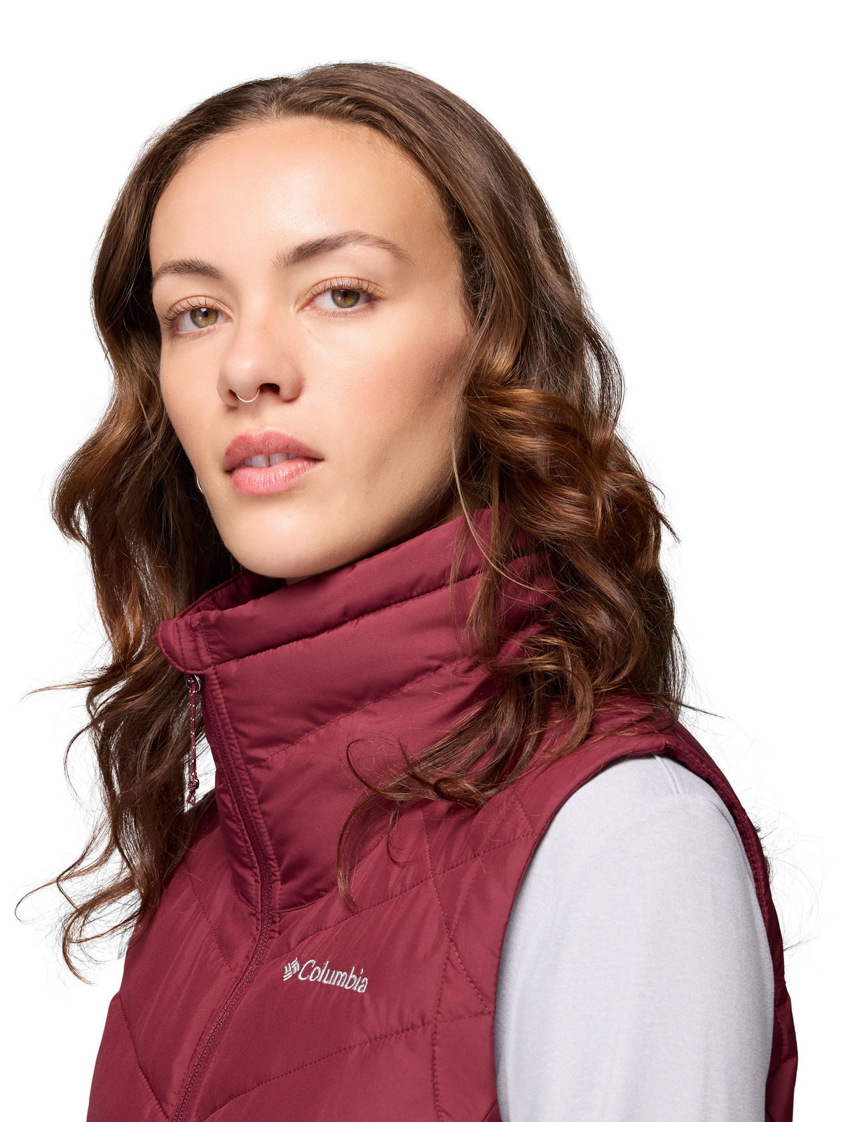 Close-up of a person wearing a burgundy Columbia Heavenly II Omni-Heat Long Vest outerwear with curly hair.