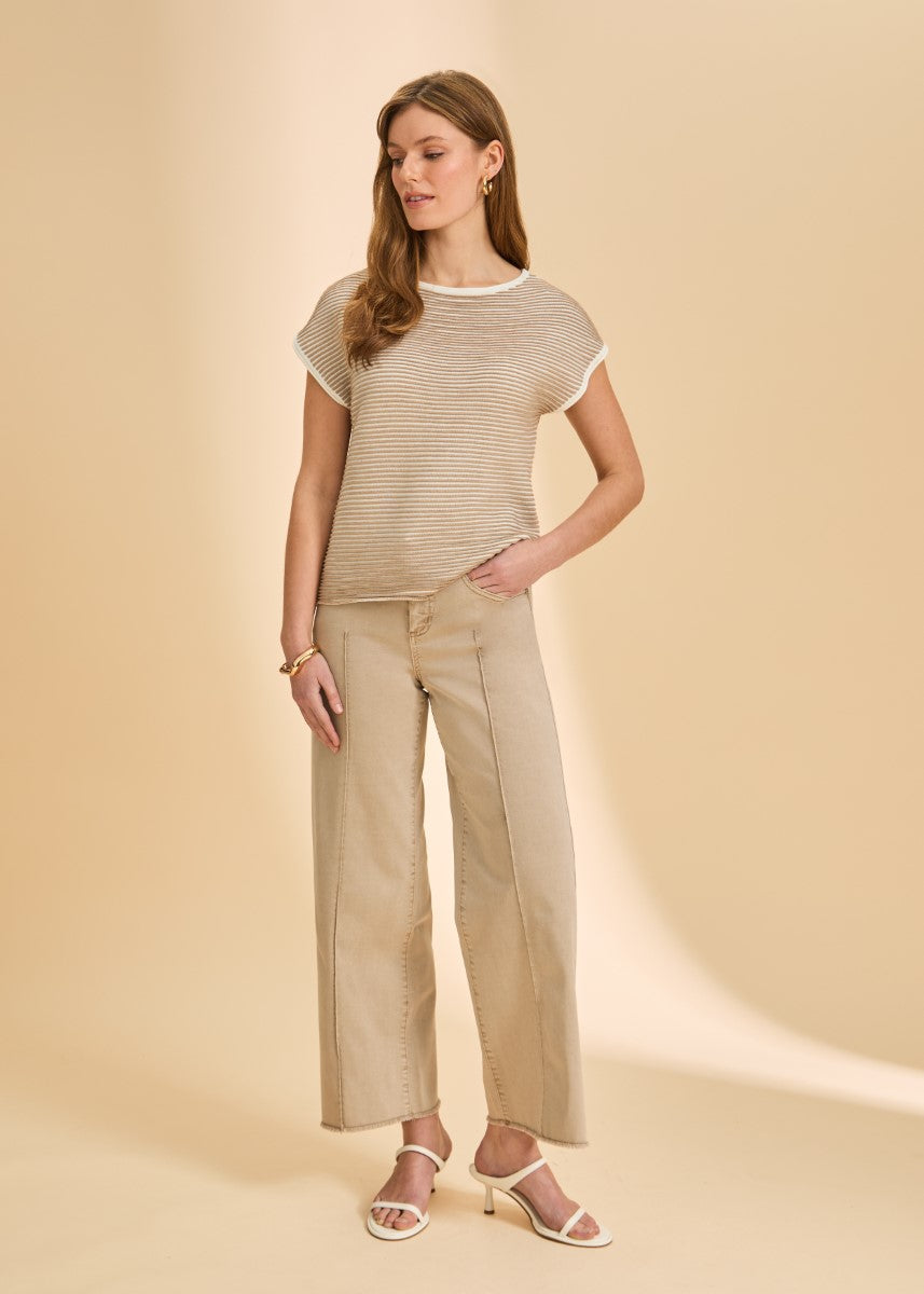 Person wearing a beige striped short sleeve top and wide-leg beige pants with white heeled sandals against a beige background