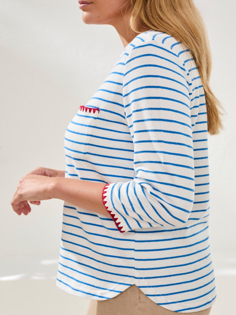White long sleeve top with blue horizontal stripes and red scalloped trim on sleeve and chest pocket edge