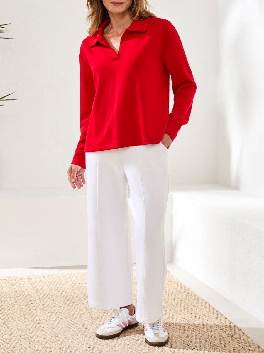 Person wearing a red long-sleeve top paired with white wide-leg pants and casual white sneakers.