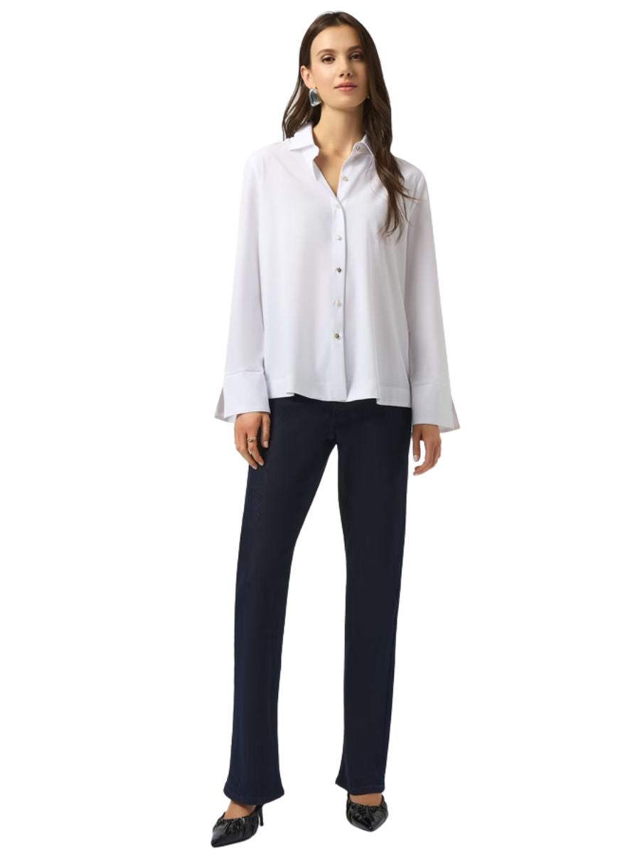 Person wearing a white long-sleeve button-up shirt and dark slim-fit pants with black pointed shoes