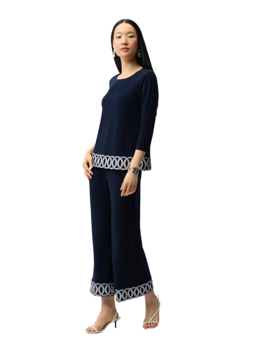 Person wearing a navy blue long sleeve top and pants with white circular pattern trim on hem and cuffs