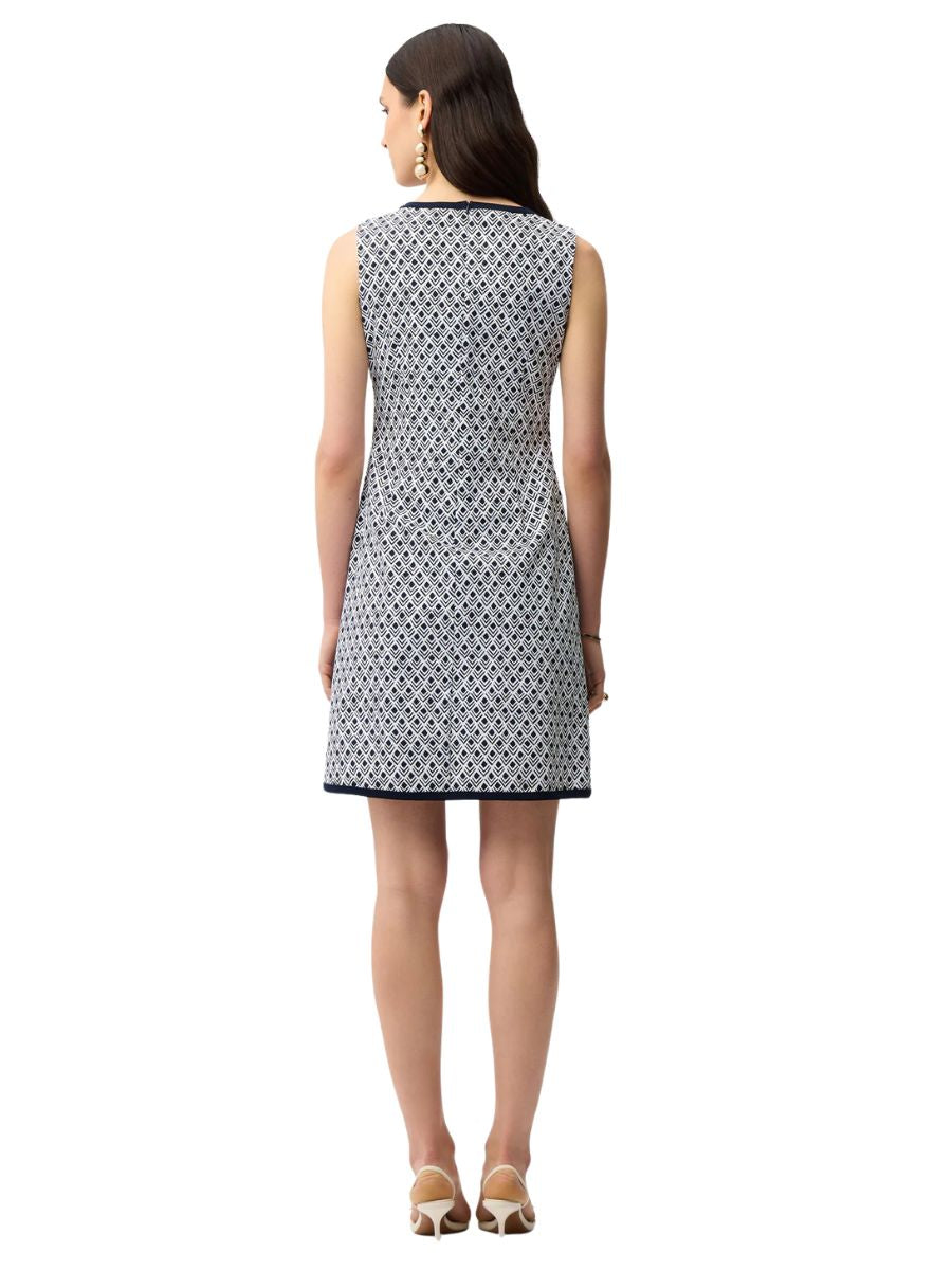 Sleeveless knee-length dress with geometric pattern in navy and white, worn with earrings and beige heels.