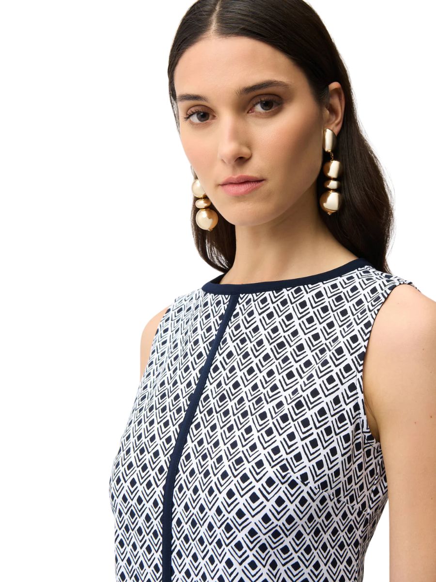 Close-up of a person wearing a sleeveless patterned top with geometric shapes and large gold statement earrings