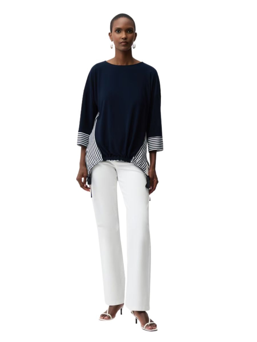 Model wearing Joseph Ribkoff Lines and Linen Asymmetric Top in navy with striped detailing and white pants by Joseph Ribkoff.