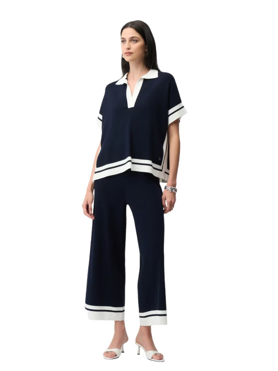 Navy blue two-piece outfit with white striped accents and a collar, styled with white open-toe heels and a bracelet.