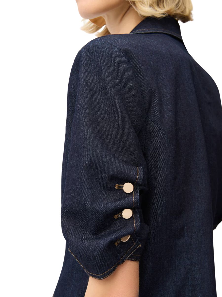 Dark denim jacket sleeve with three light buttons on a rolled-up cuff detail against a white background