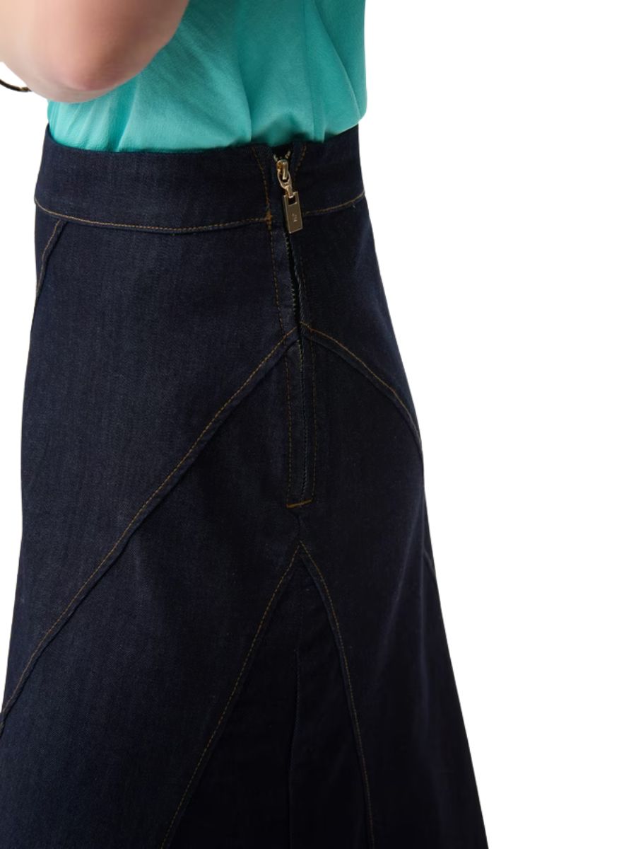 Close-up of a dark denim skirt with detailed stitching and a gold zipper, paired with a light teal top.