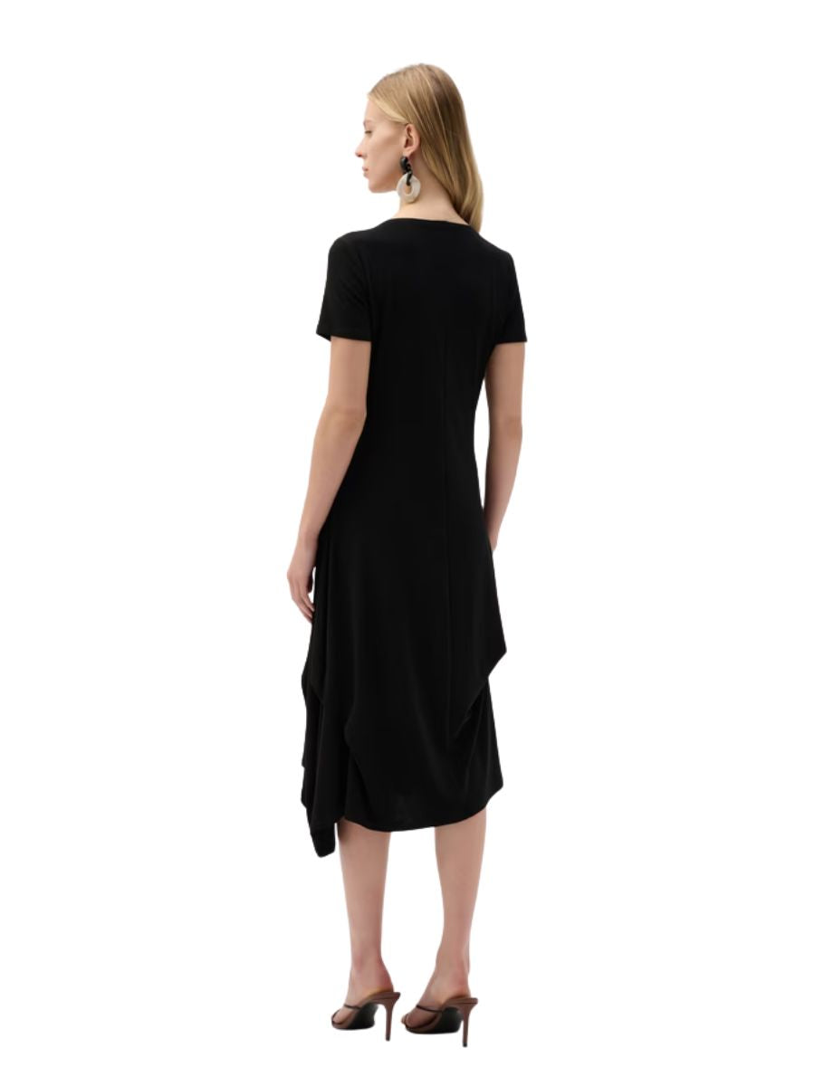 Person in a black asymmetrical hem dress with short sleeves and heeled mules, facing away from the camera.