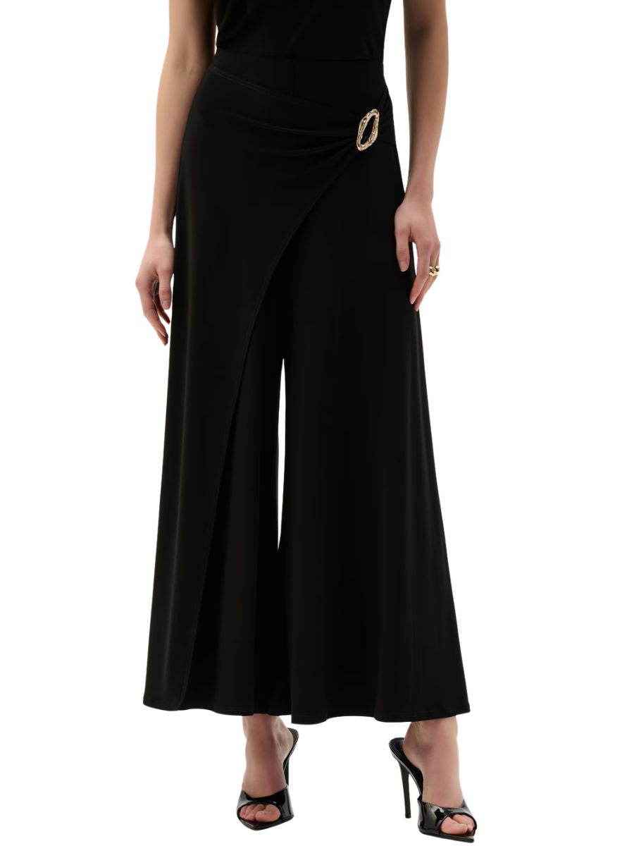Black wide-leg trousers with an asymmetrical wrap detail and decorative buckle at the waist