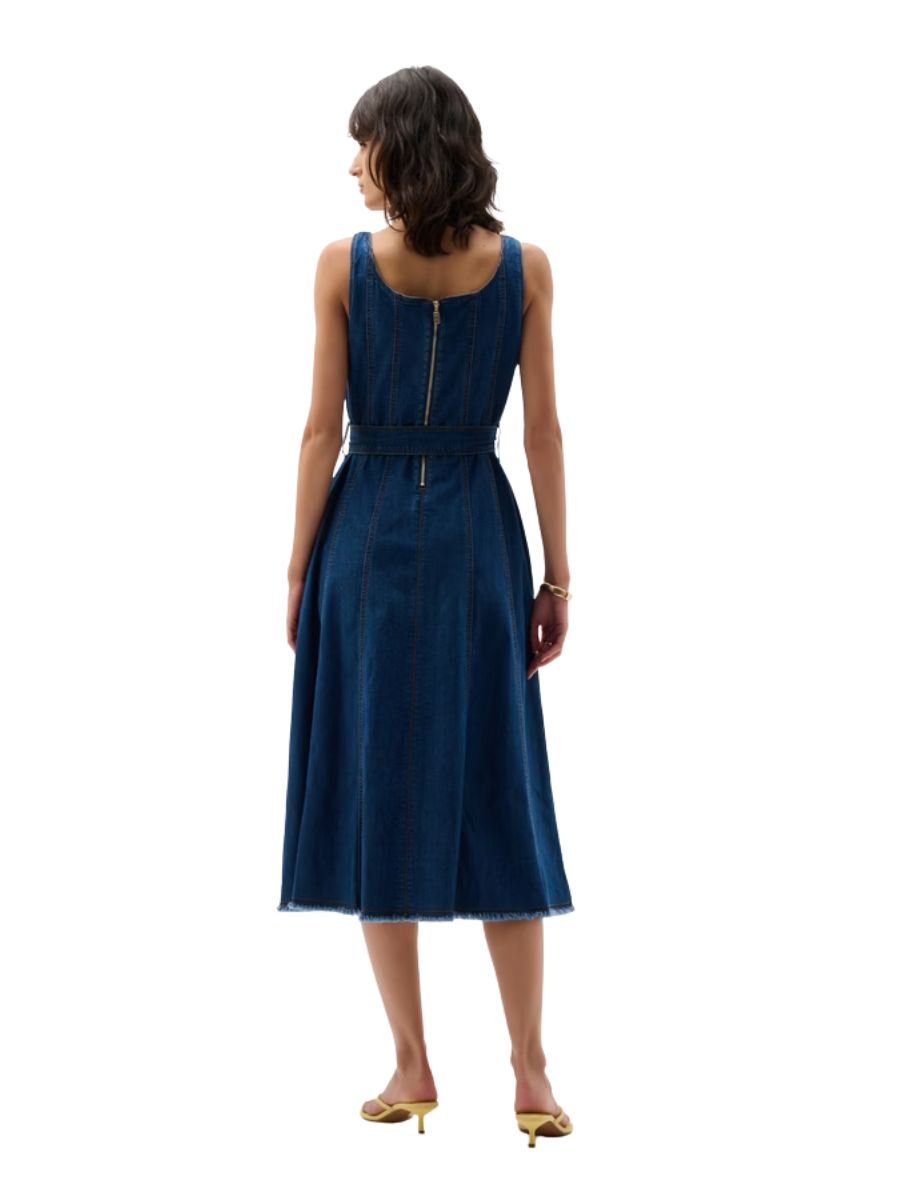 Back view of a sleeveless midi denim dress with a belt and a back zipper, worn with open-heeled shoes.