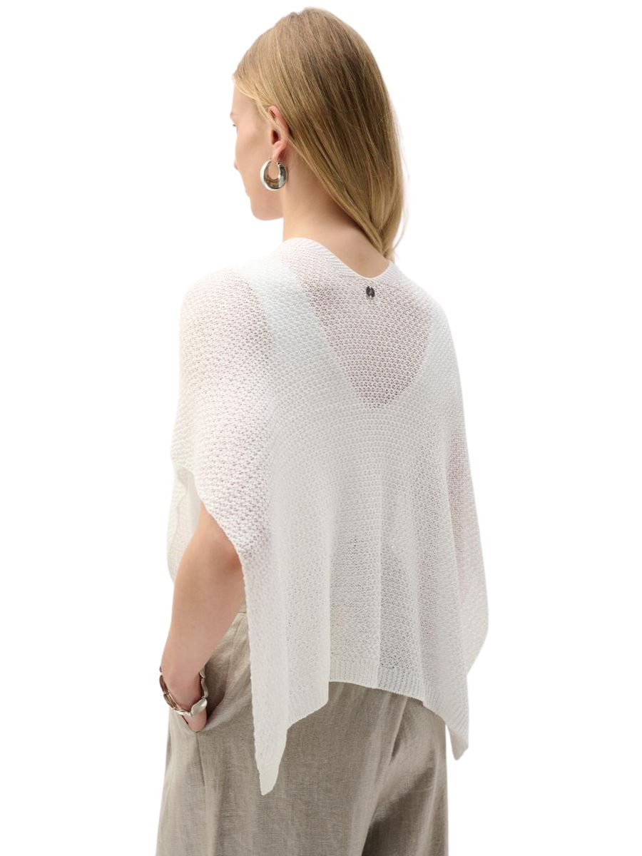 Back view of a person wearing a loose, textured white knit top with light beige pants and large hoop earrings