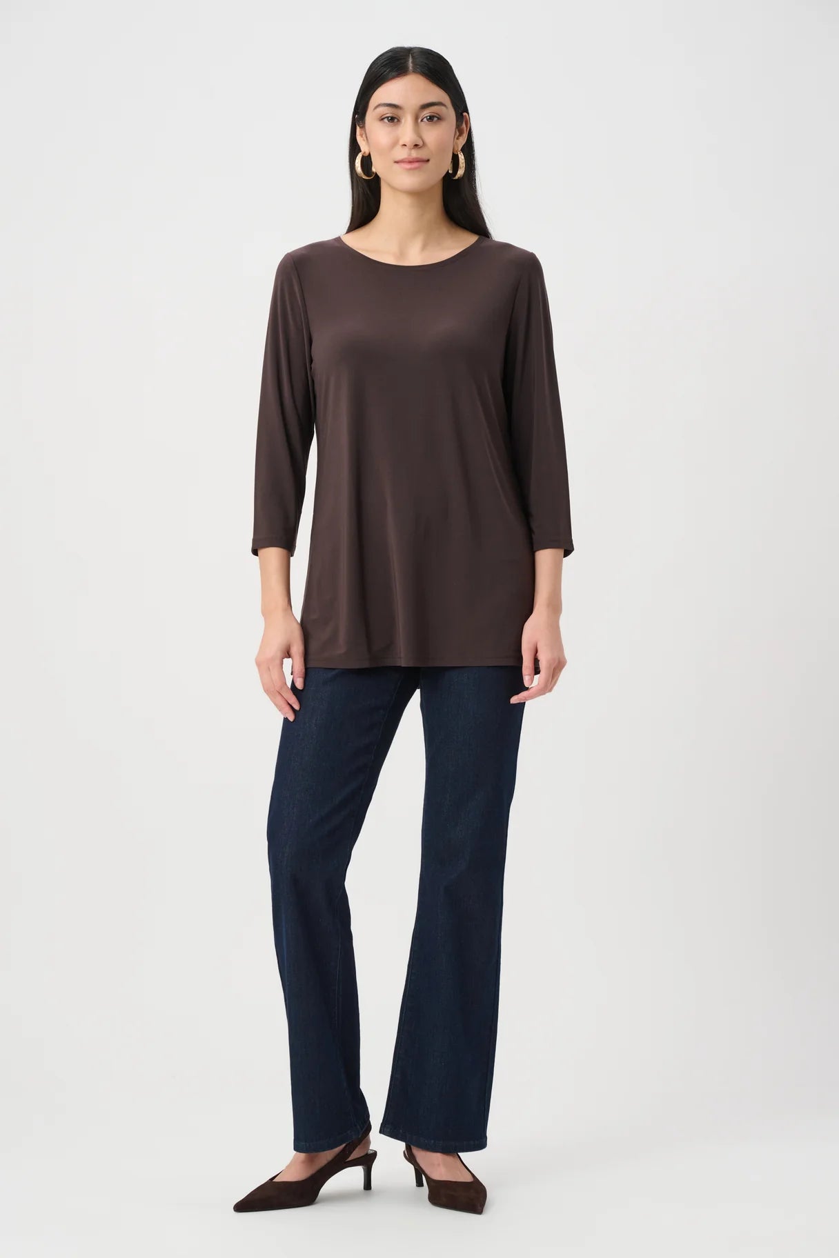 Long-sleeve mocha brown top paired with dark blue denim jeans and brown pointed-toe heels on a plain background.