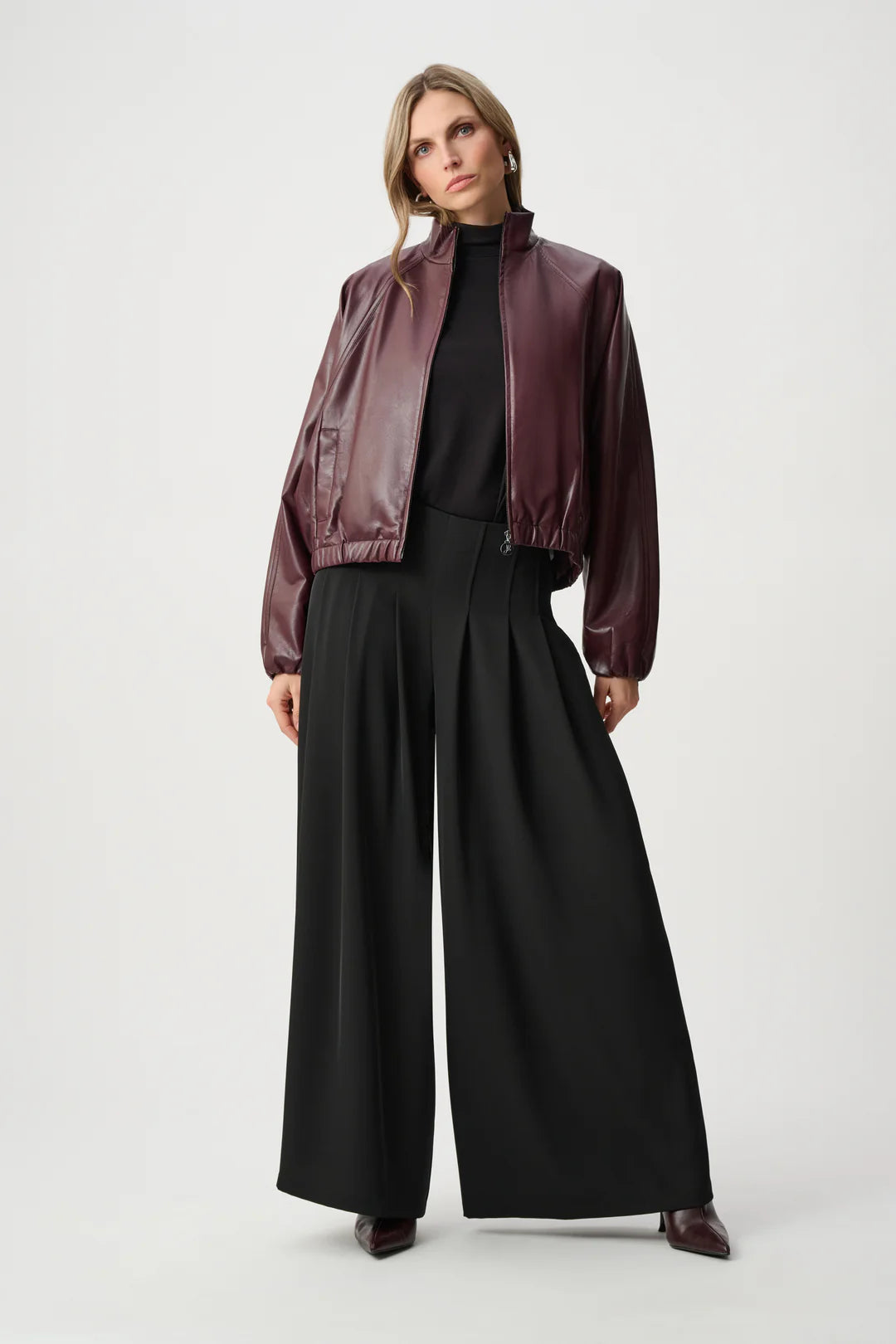 Burgundy leather jacket paired with black high-waisted wide-leg pants and a black top on a light background.