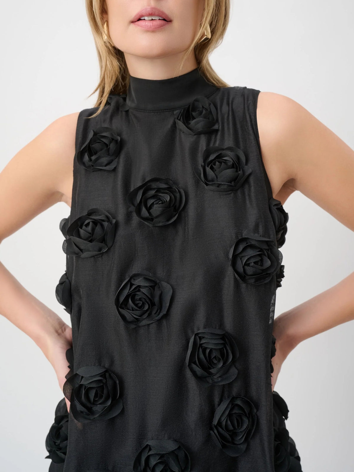 Sleeveless black top with high neckline adorned with textured black rose appliques on front and sides.
